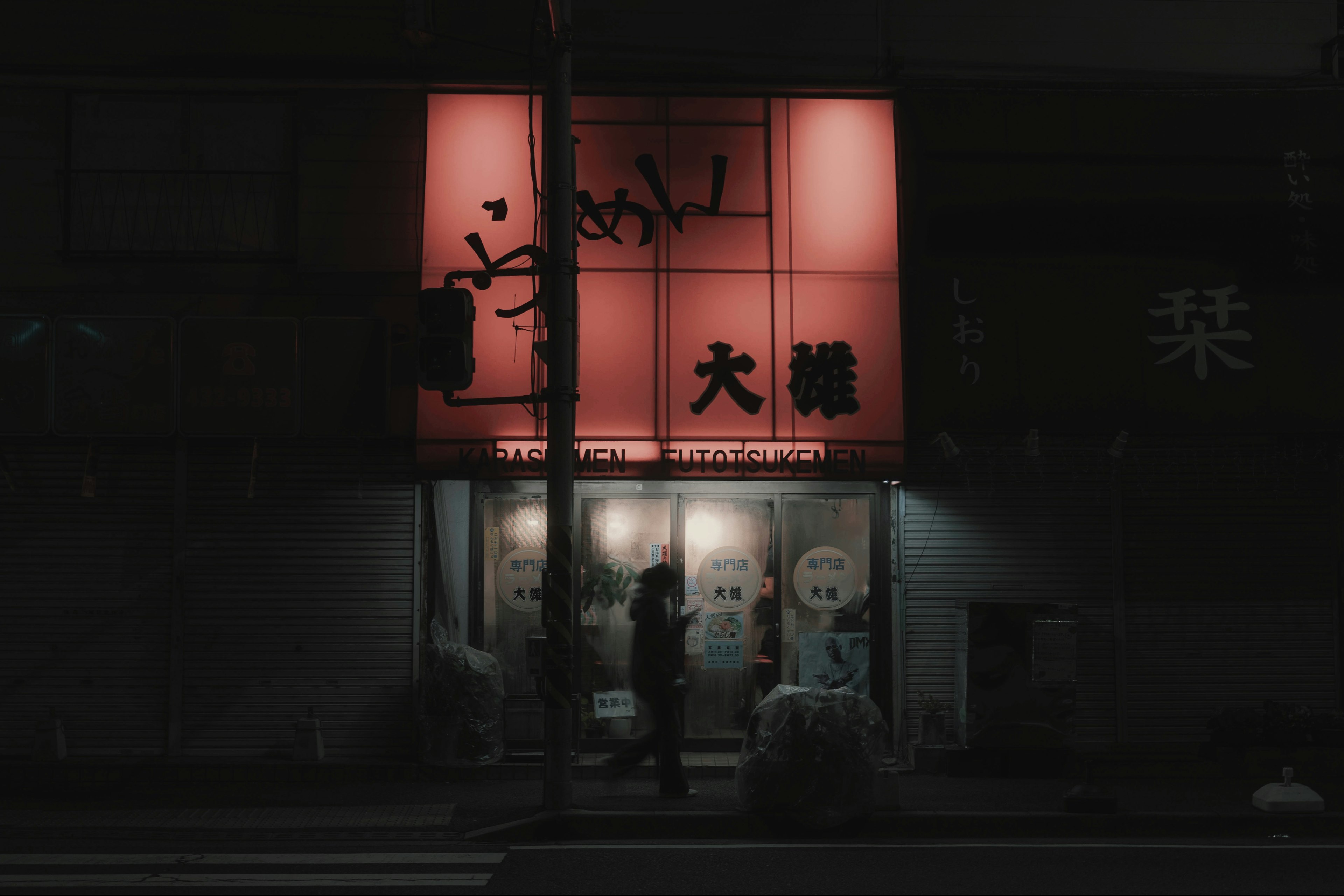 Ramen shop with a red sign in a nighttime urban setting