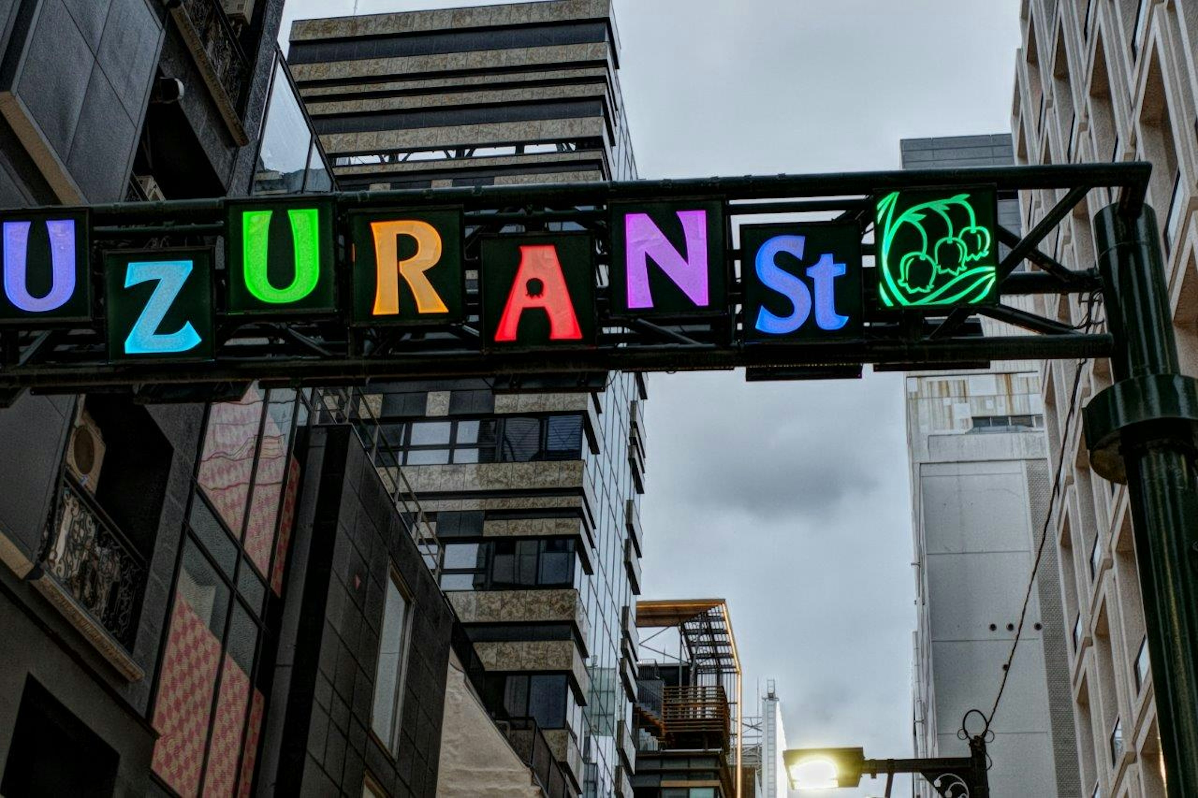 Insegna colorata con la scritta 'UZURAN St' in un contesto urbano