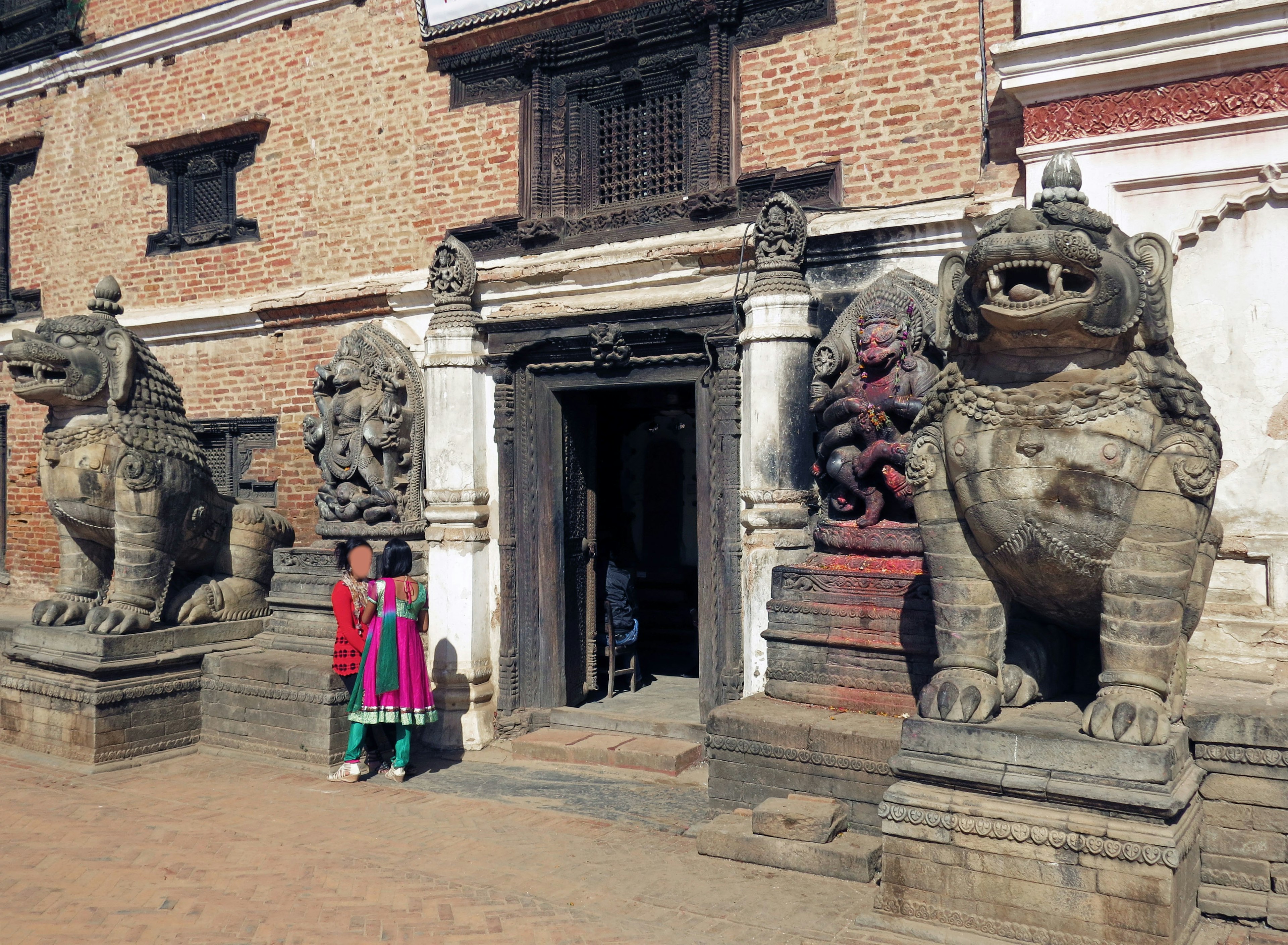 Photo d'une personne se tenant à l'entrée d'un vieux bâtiment avec des statues de lions