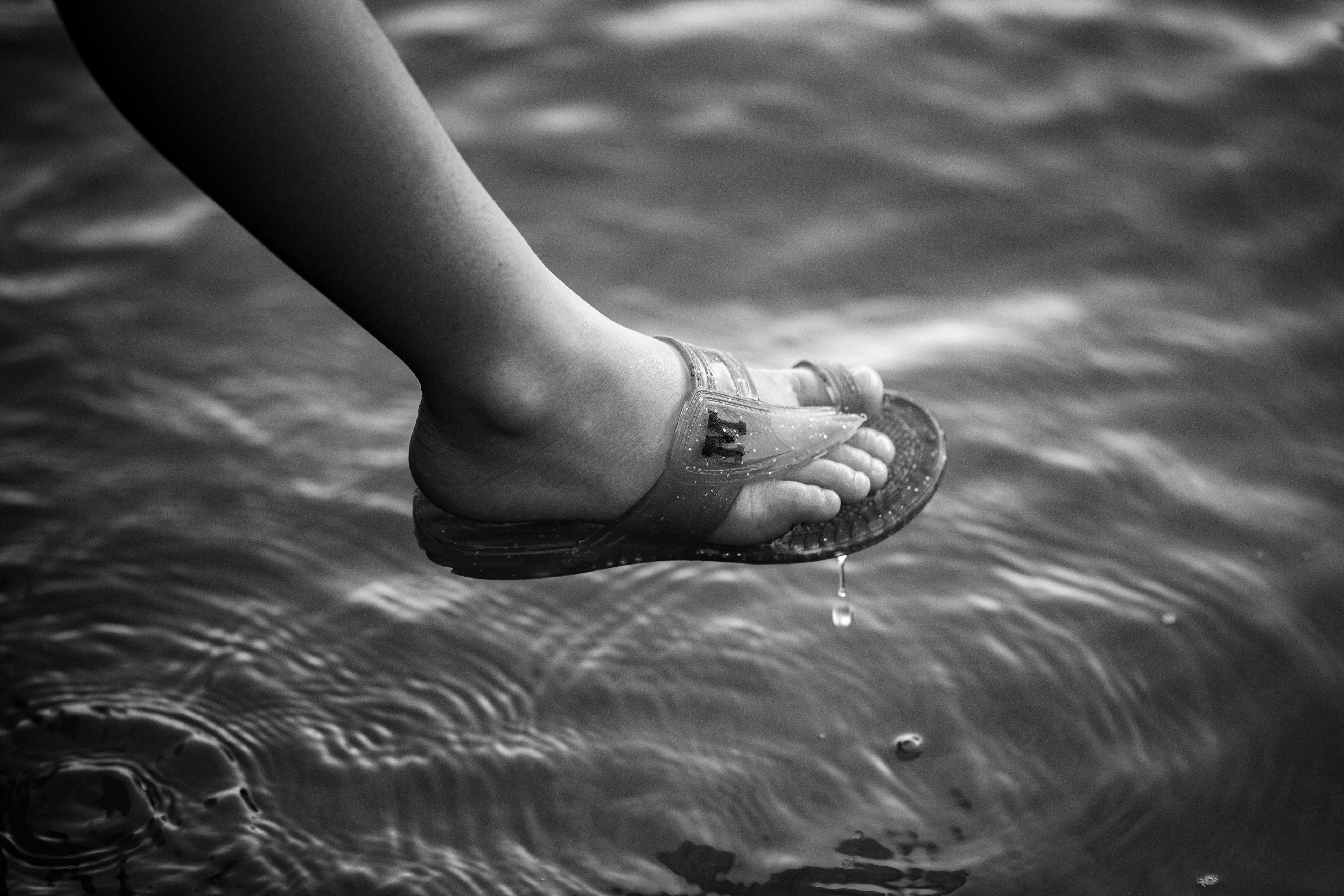 Fuß in einer Sandale auf der Wasseroberfläche