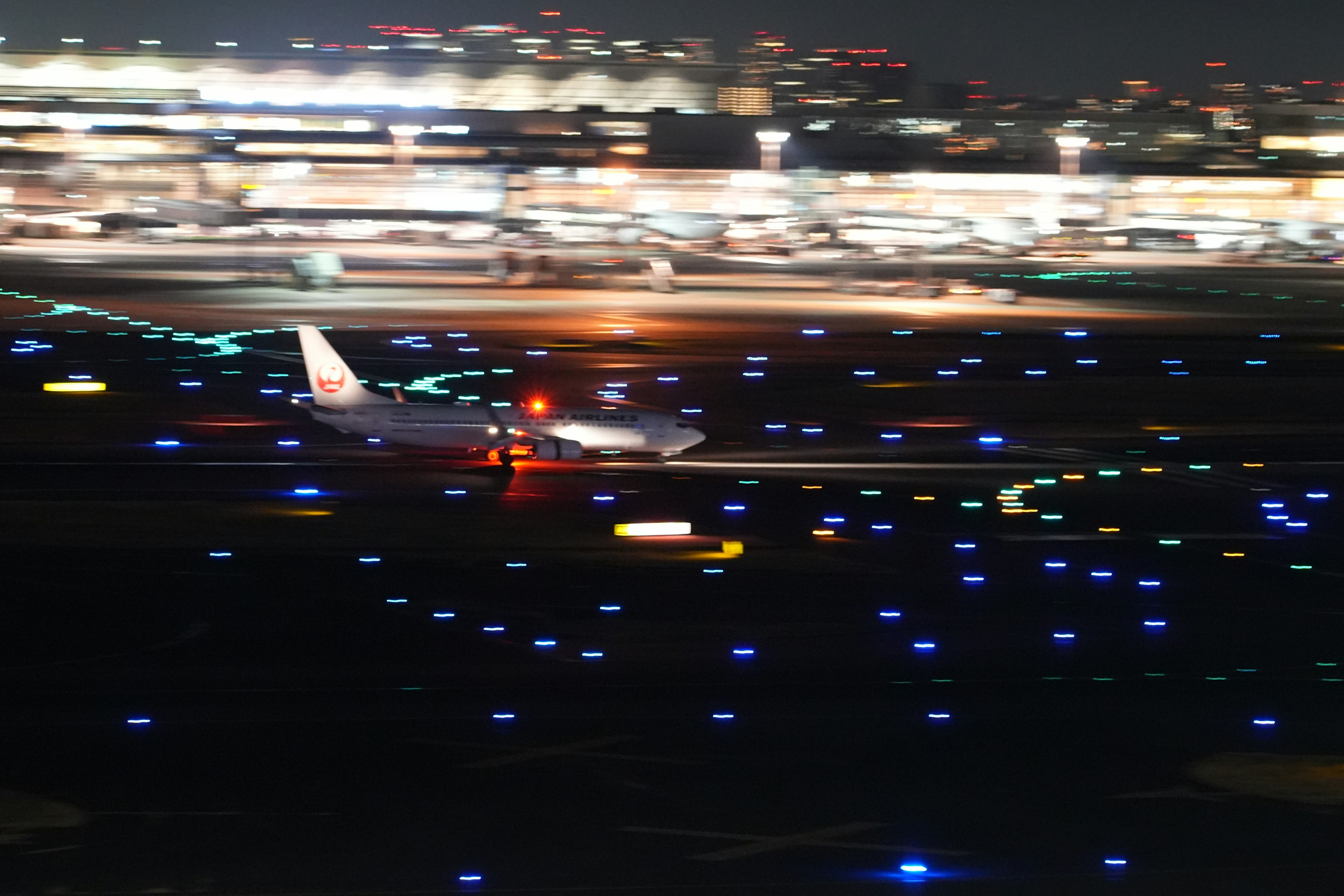 Aereo in taxi sulla pista di notte con luci brillanti dell'aeroporto