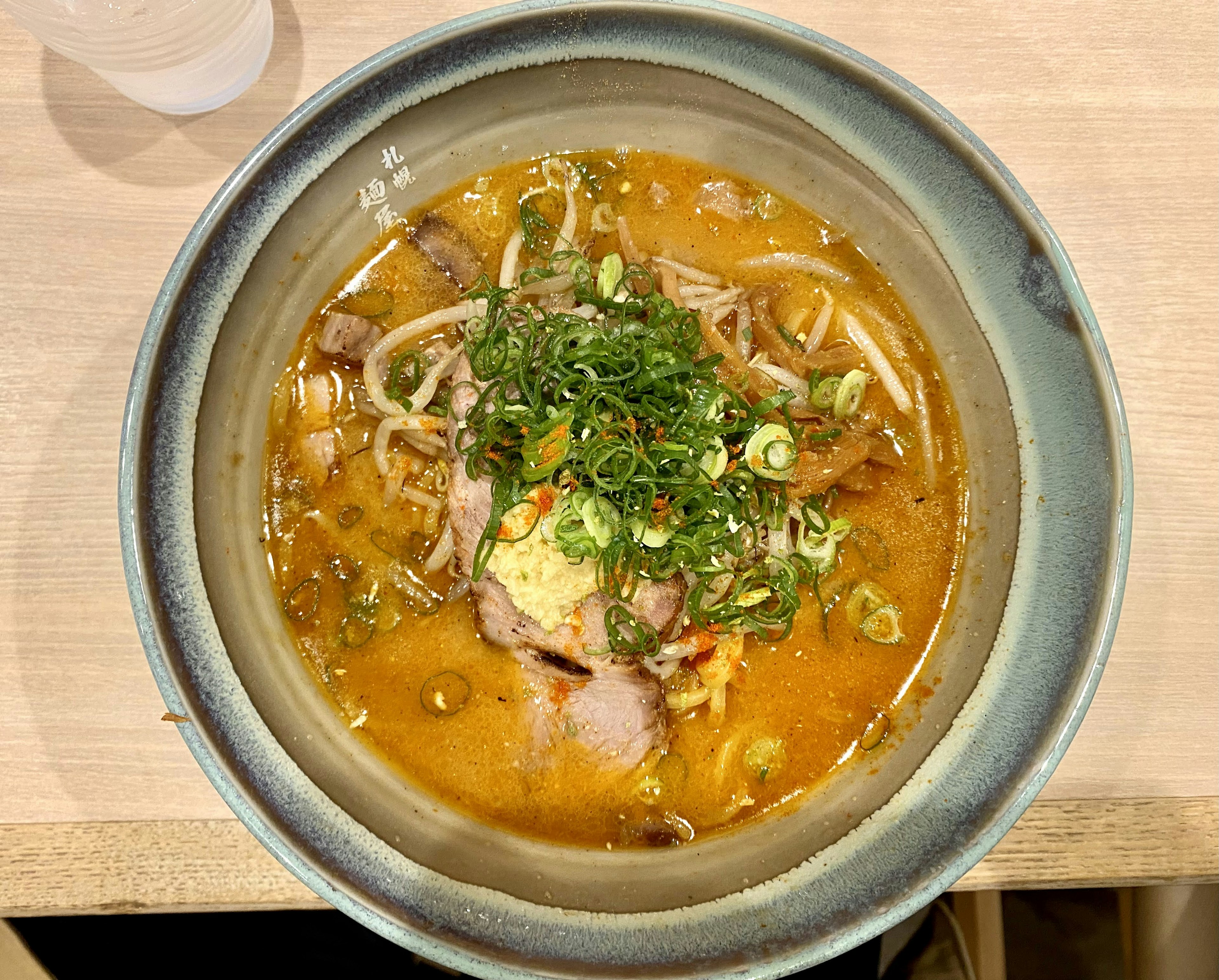 美味しそうなラーメンのボウルにトッピングされたネギとチャーシュー