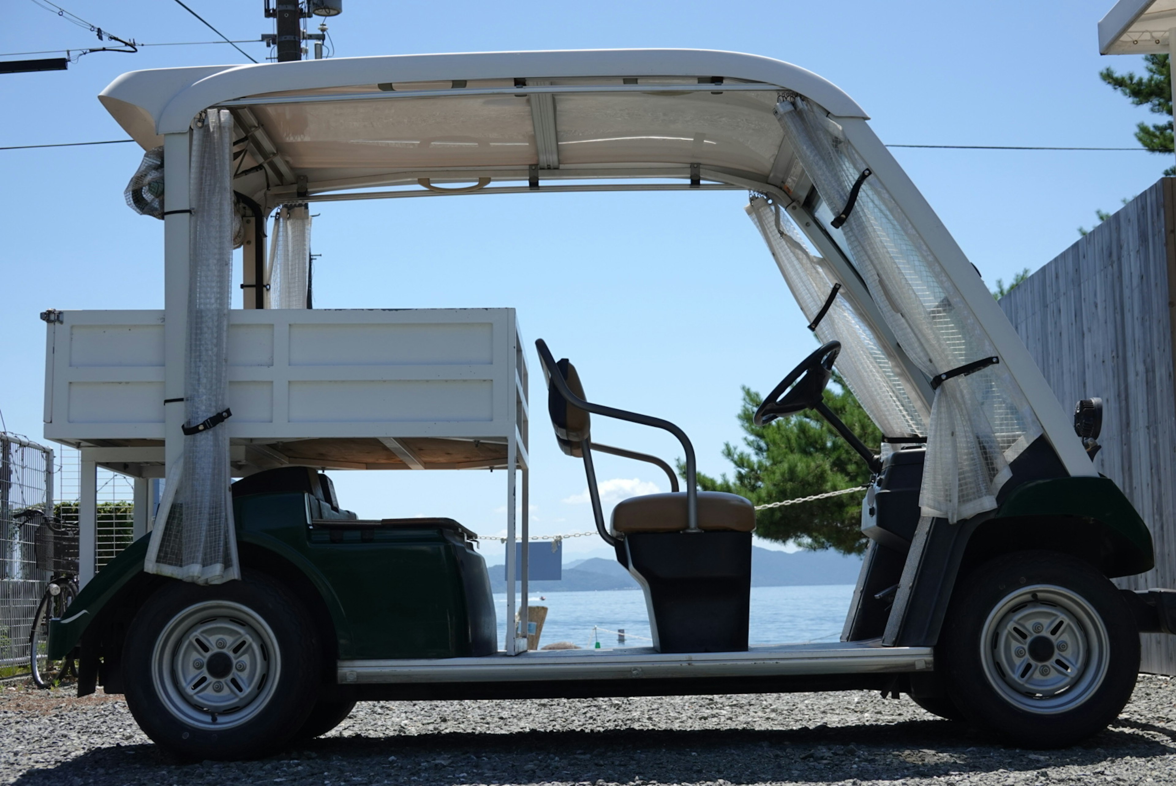 Kendaraan golf hijau dengan kanopi putih terlihat dari samping