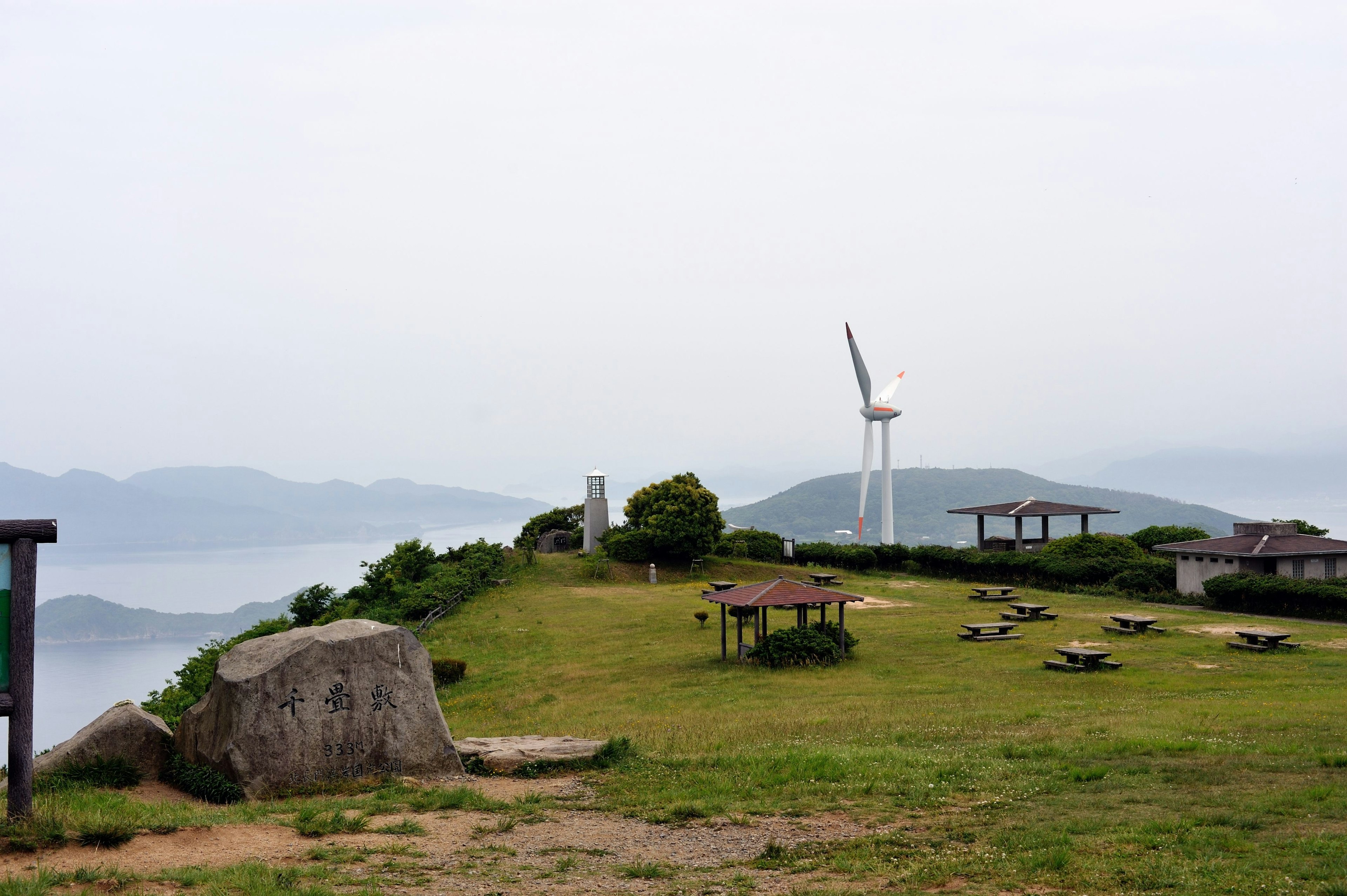 風力発電機がある緑豊かな丘の風景 休憩エリアとテーブルが点在する