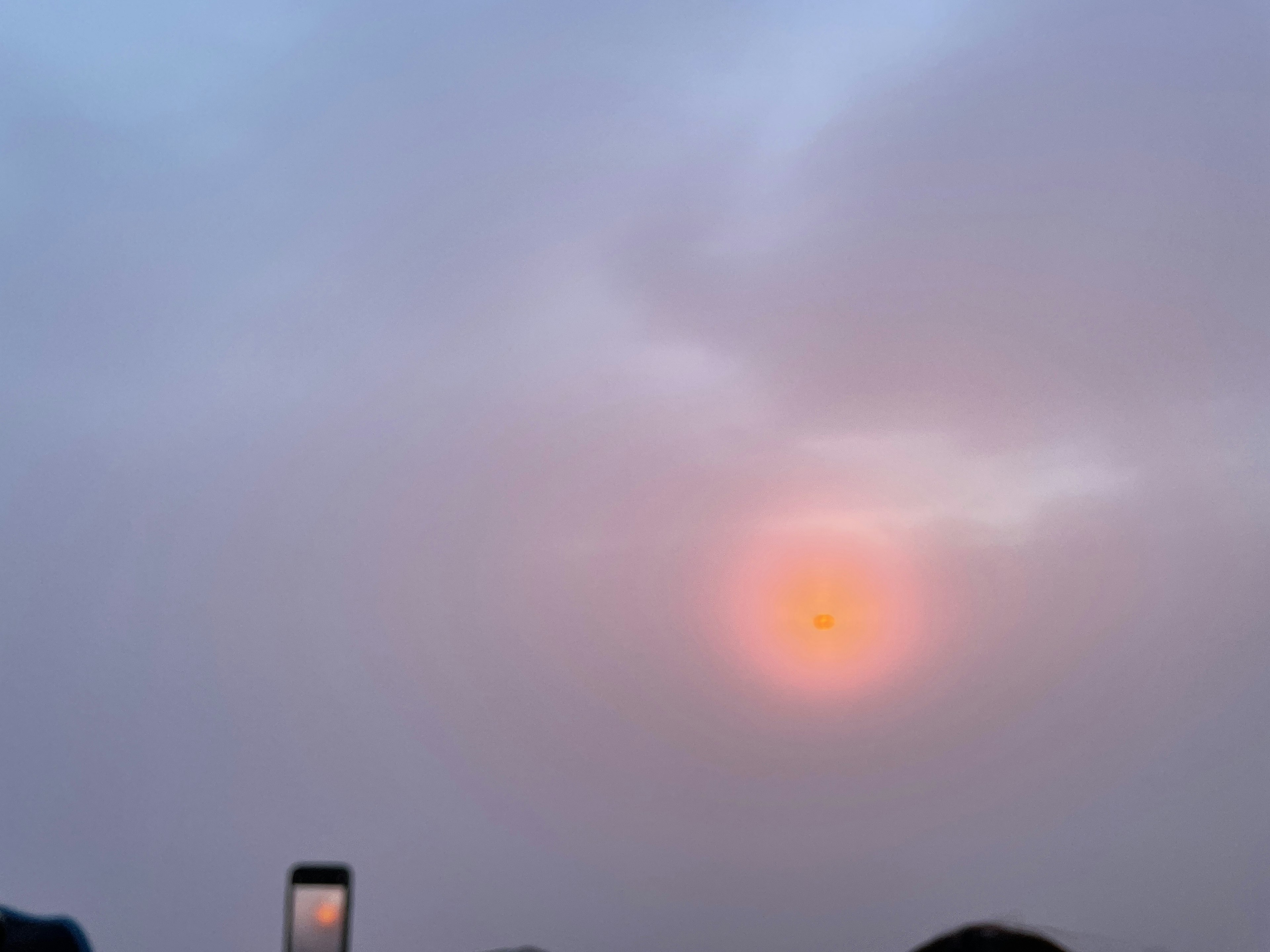 Orange sun in a hazy sky with soft clouds