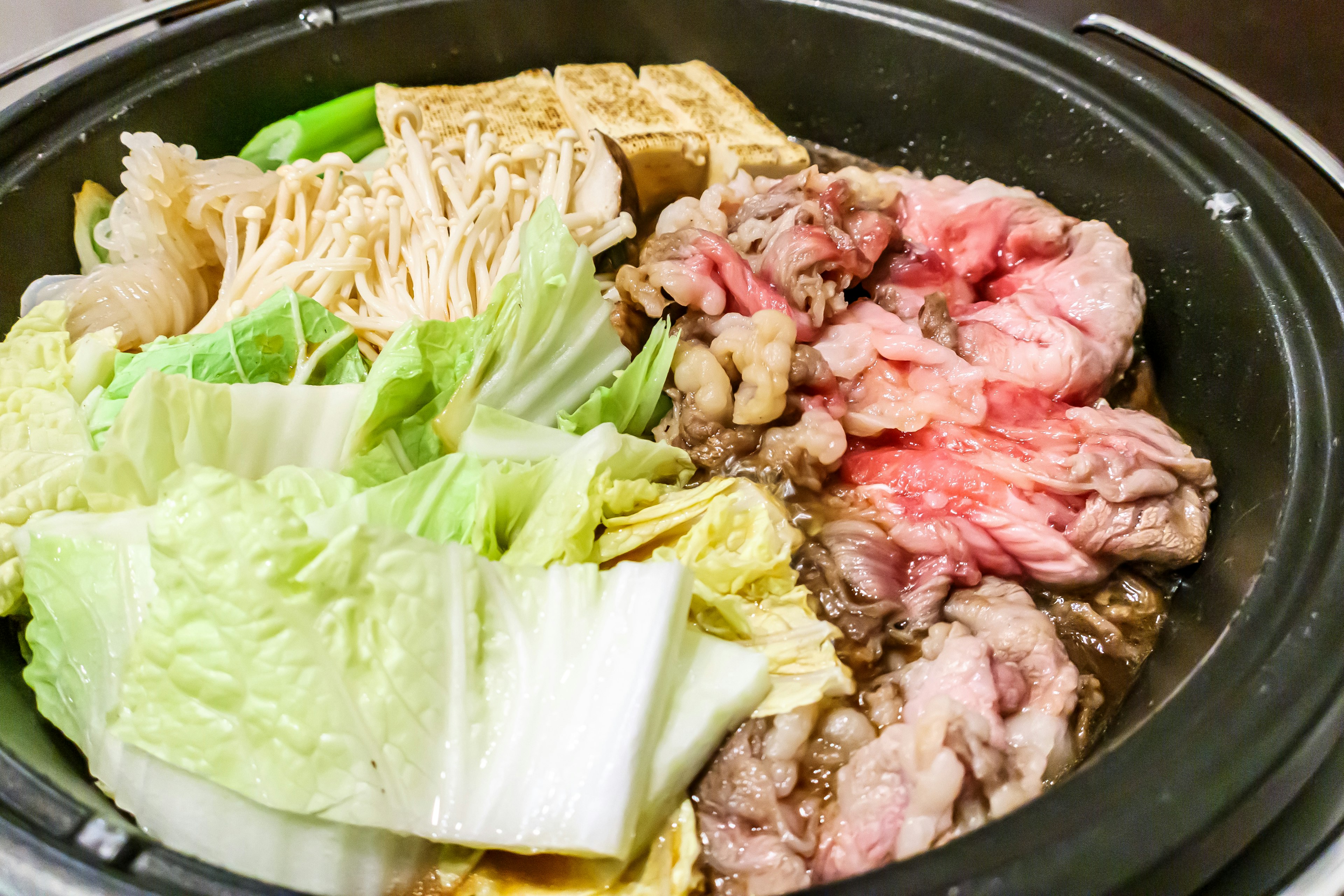 Fresh meat and vegetables arranged in a hot pot