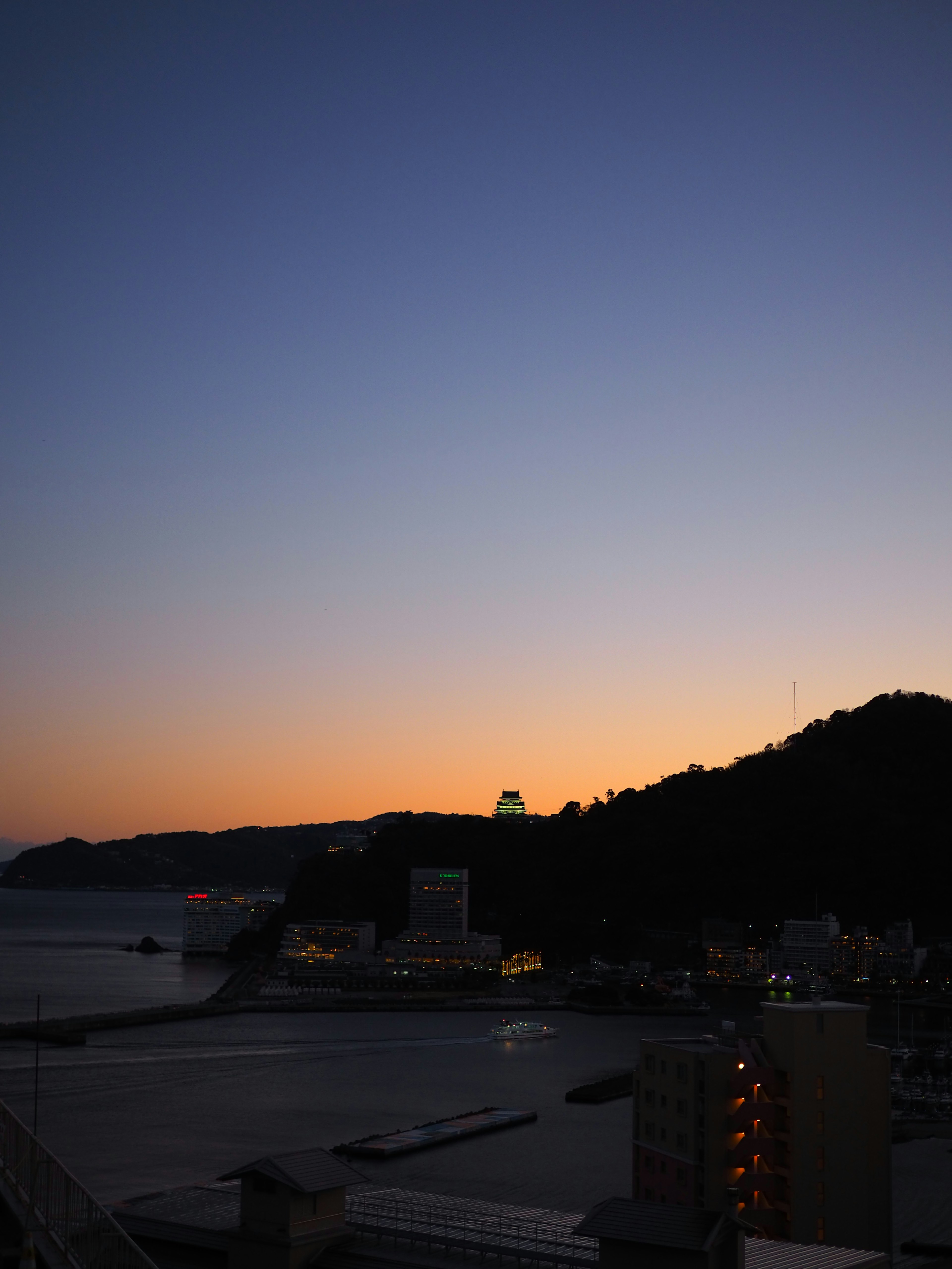 夜明けの海と山の景色に薄明るい空が広がる