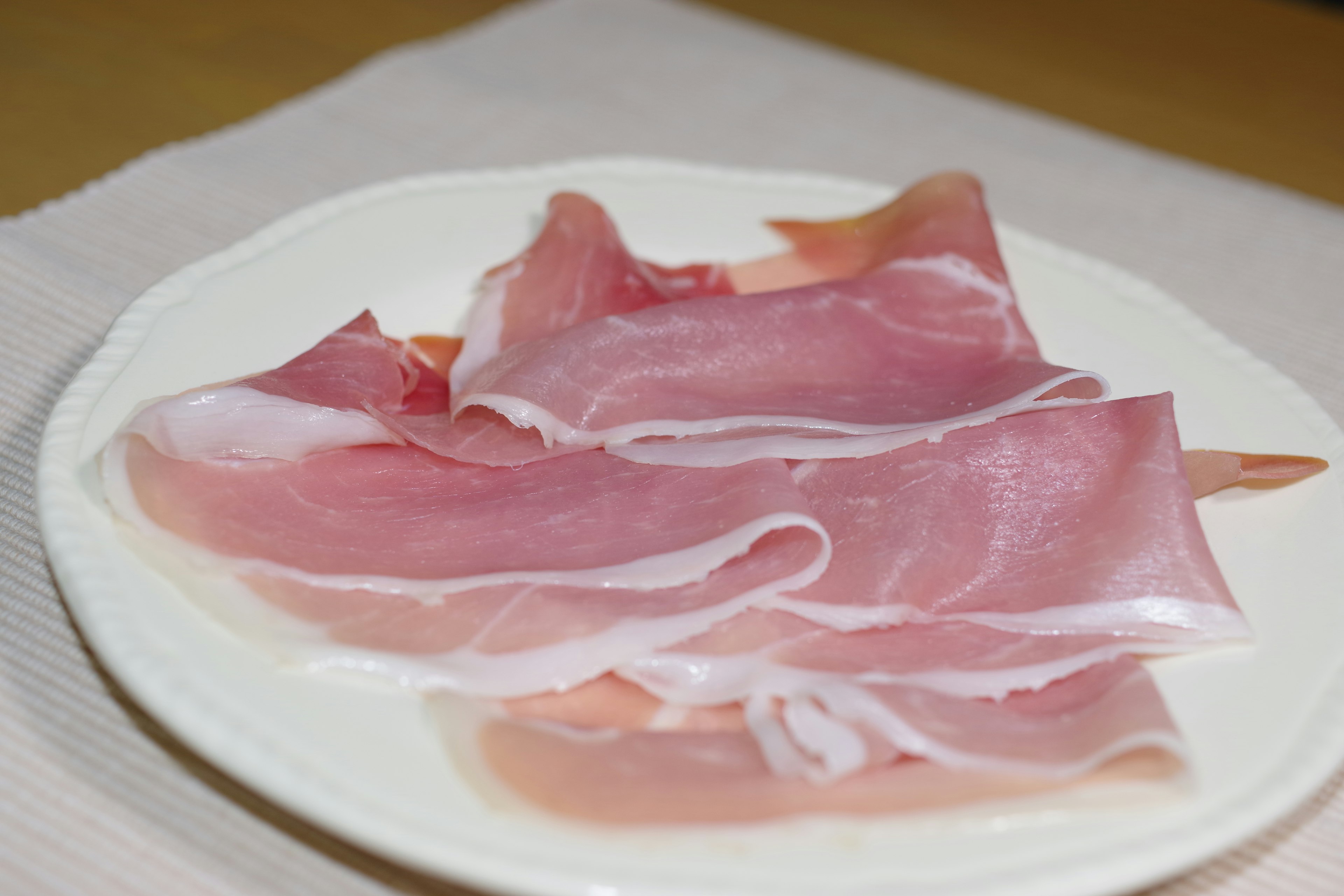 Thinly sliced ham arranged on a white plate