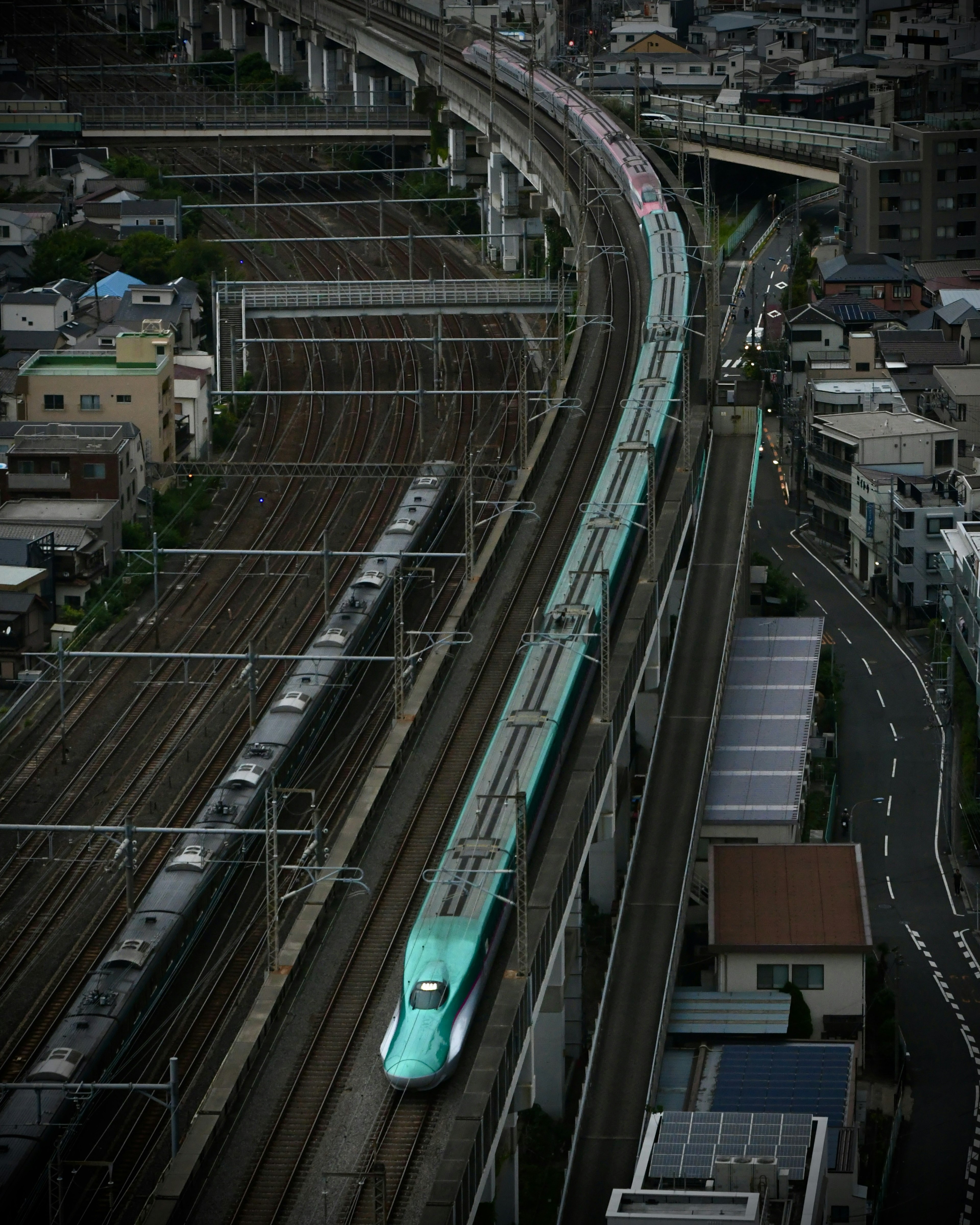 Shinkansen train traveling on curved tracks in an urban landscape