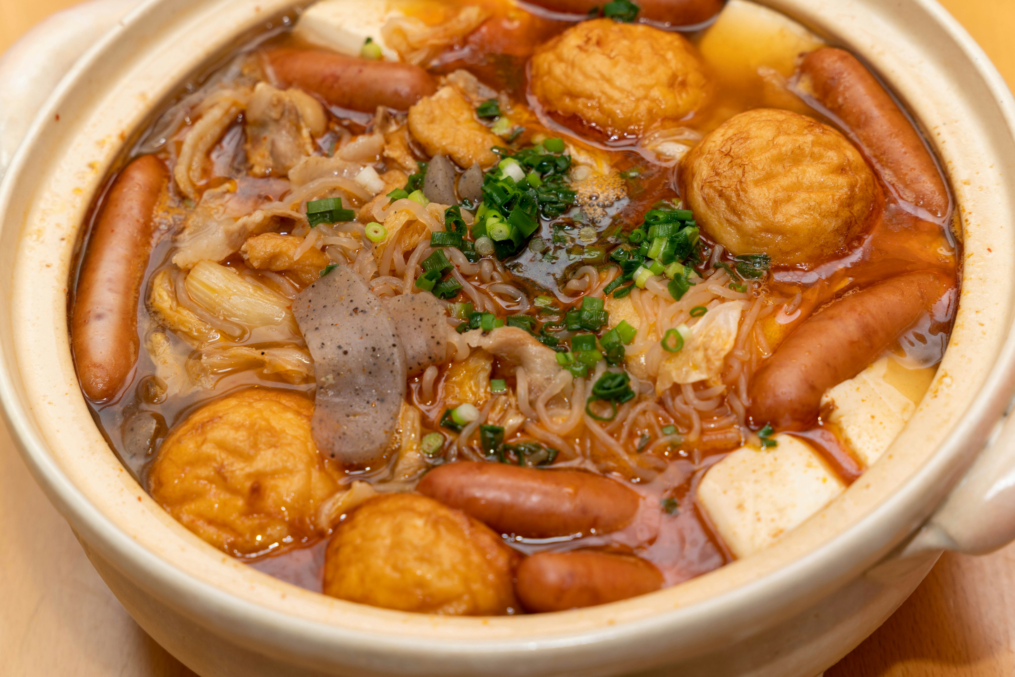 Un plat de pot chaud avec divers ingrédients y compris des saucisses des boulettes de viande et du tofu