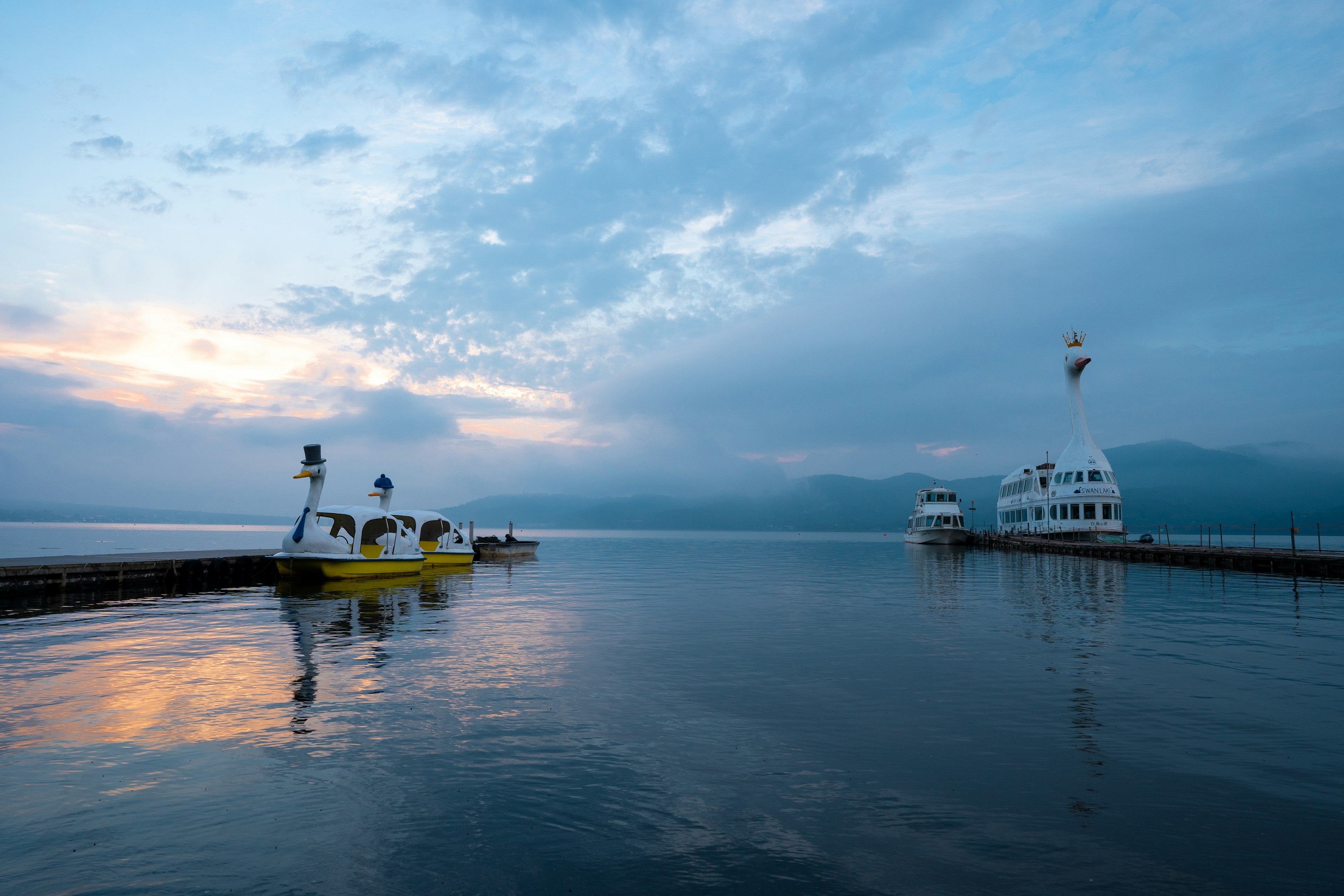 Pemandangan perahu kuning dan kapal putih di atas air tenang