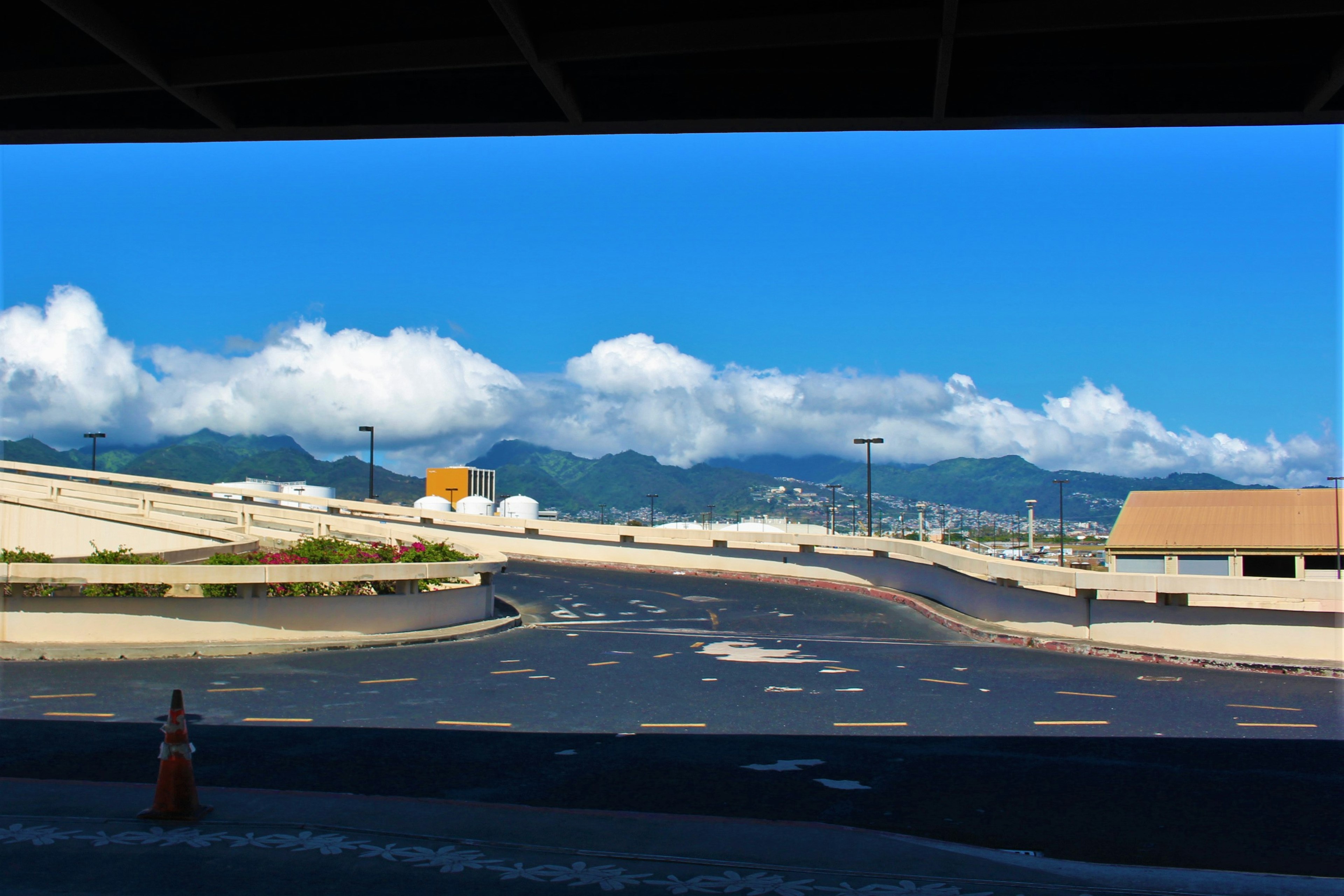 青空と白い雲が広がる風景の下に道路と建物が見える