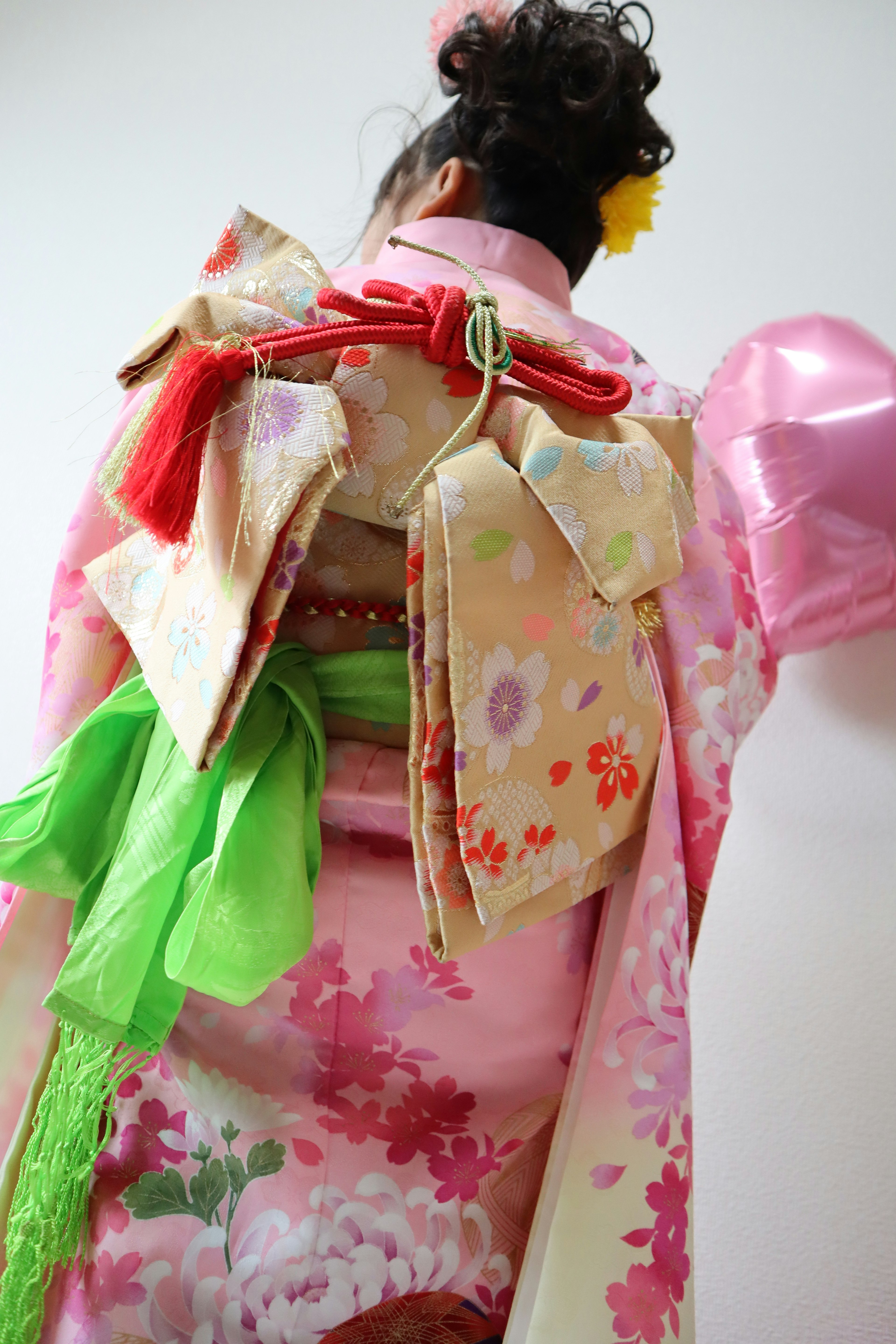 Hình ảnh từ phía sau của một người phụ nữ trong kimono rực rỡ với obi đầy màu sắc