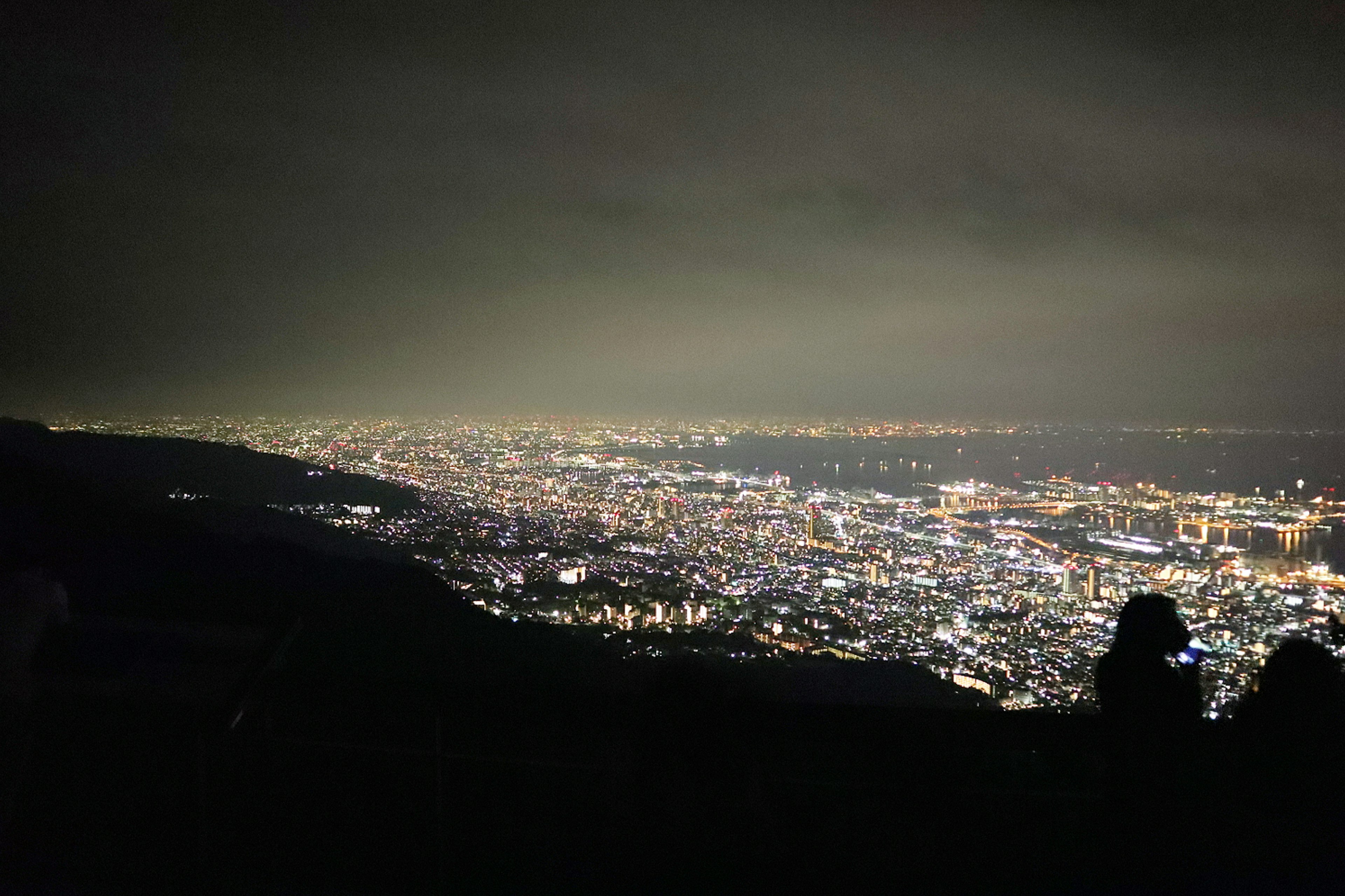 Panoramic view of a city at night with bright lights from a mountain