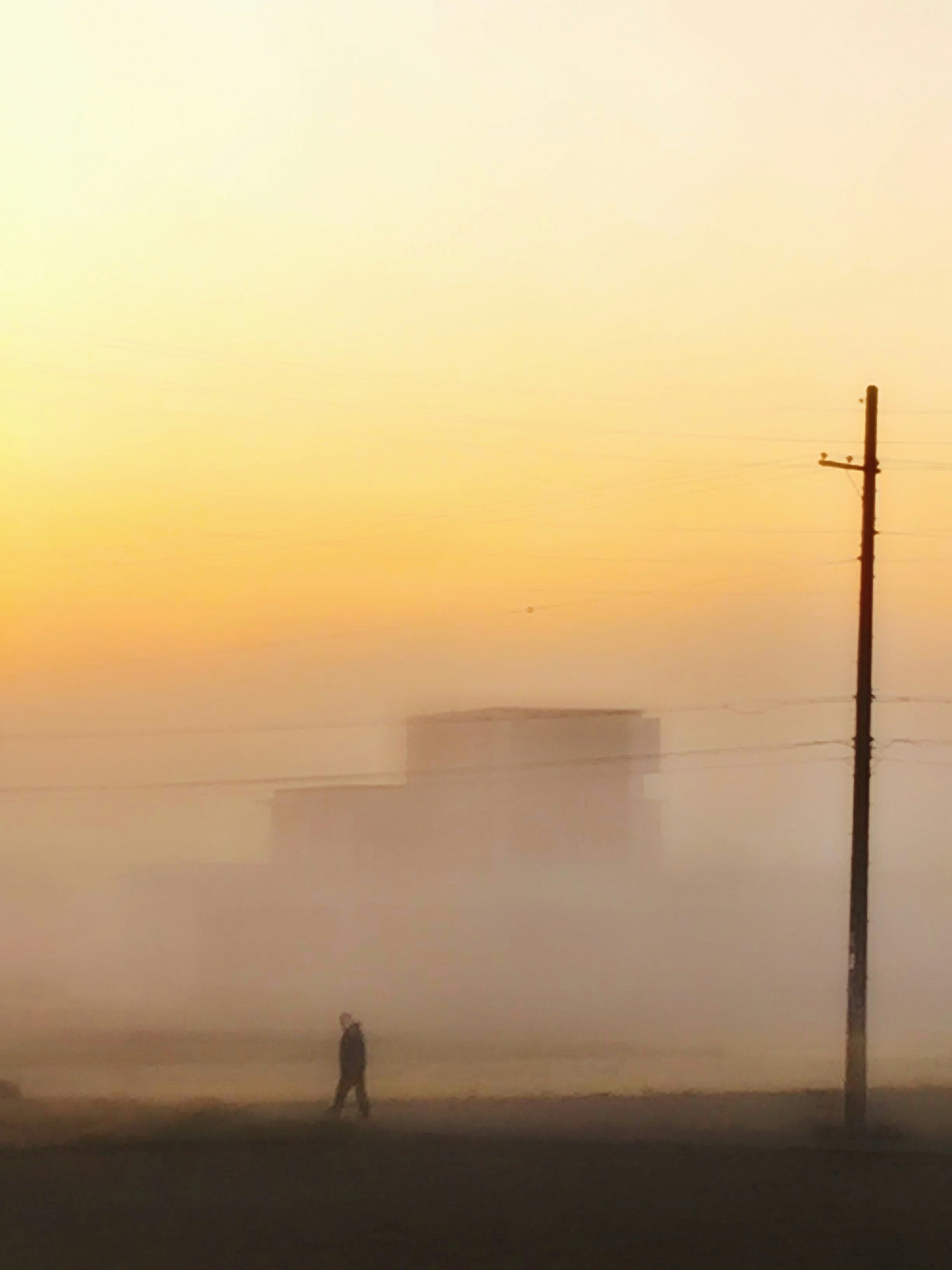 Silhouette einer Person, die durch den Nebel geht, mit einem Gebäude im Hintergrund