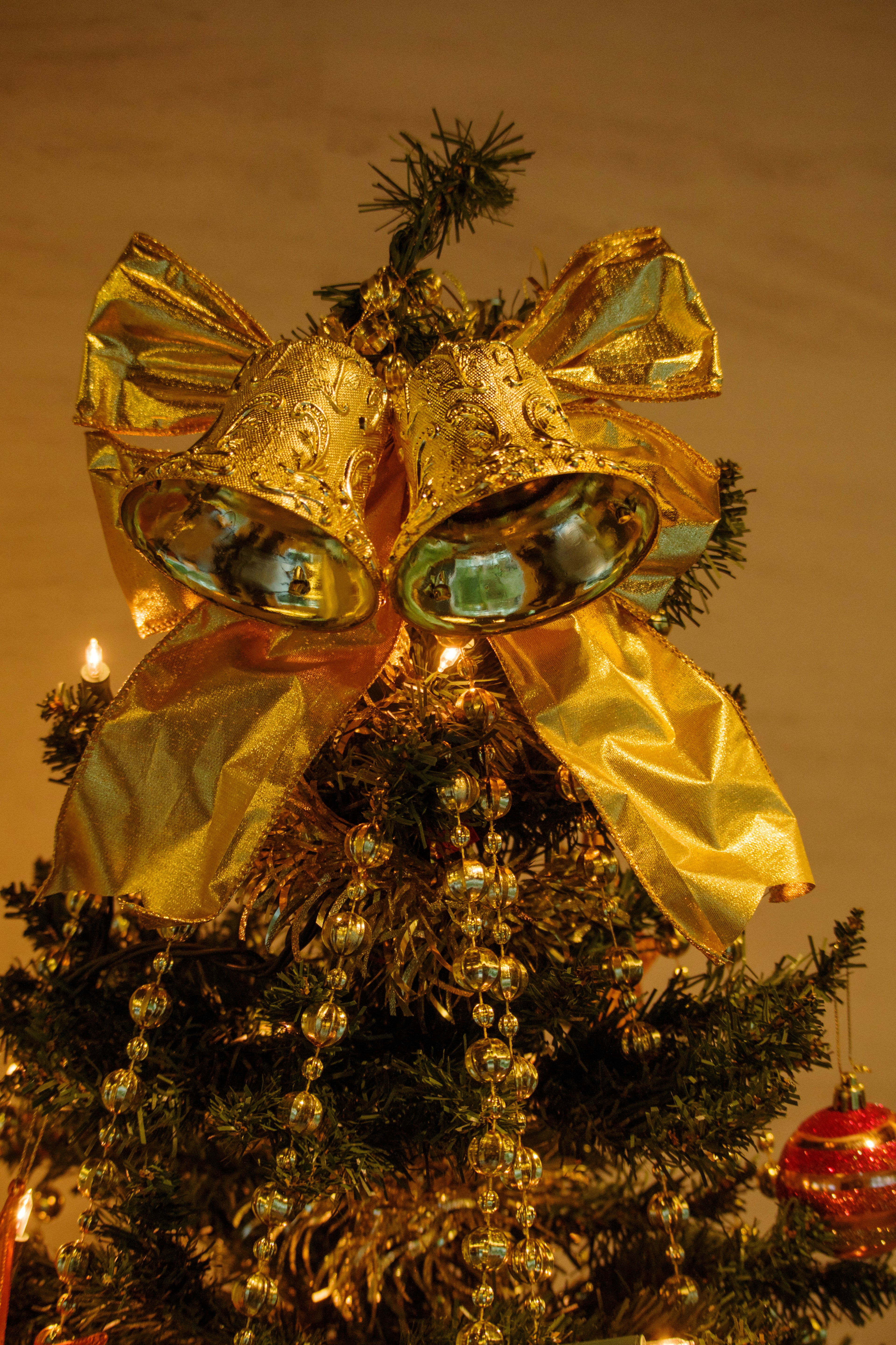 Campane dorate e nastro sulla cima di un albero di Natale