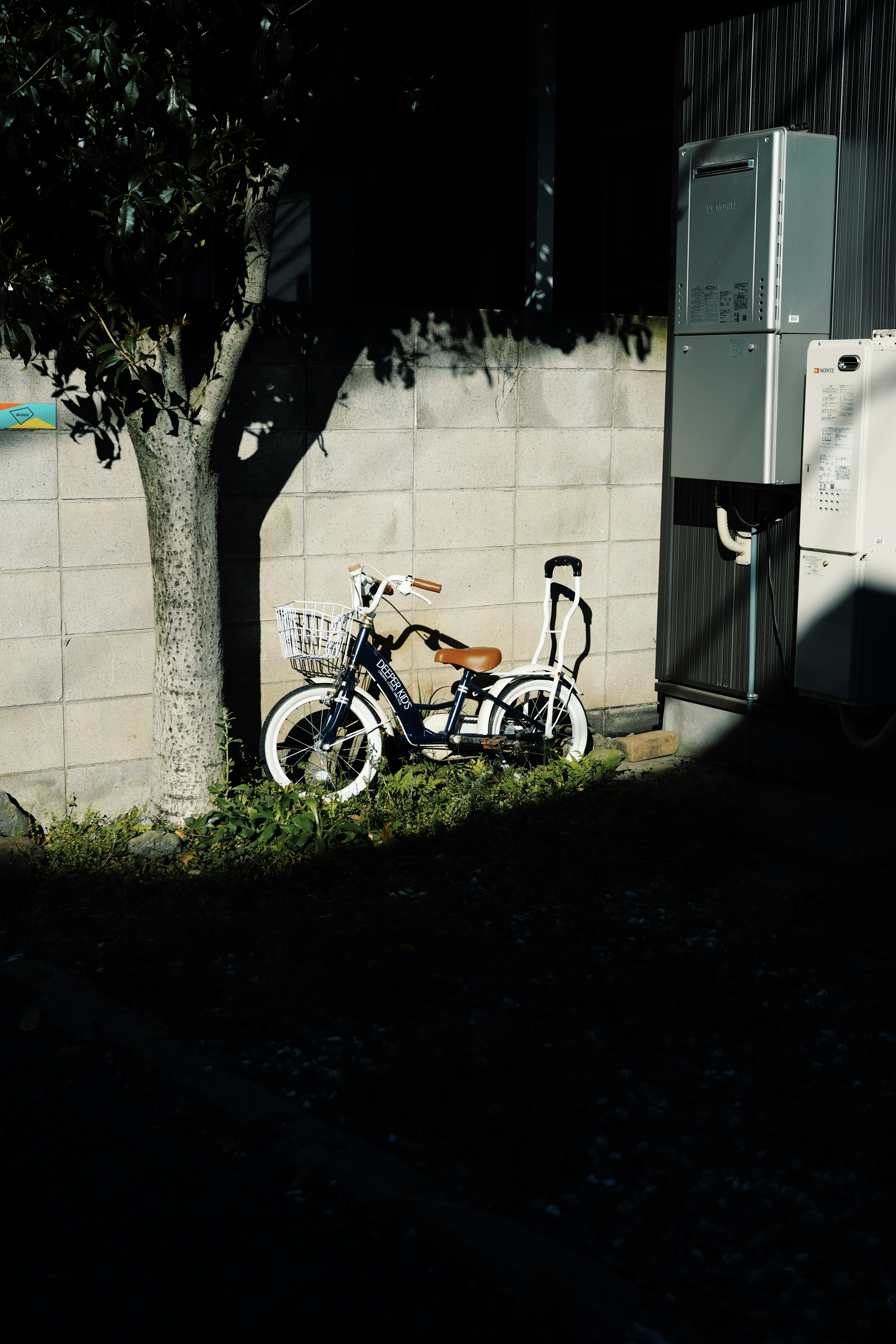 白い自転車が木のそばに置かれている壁の前の風景