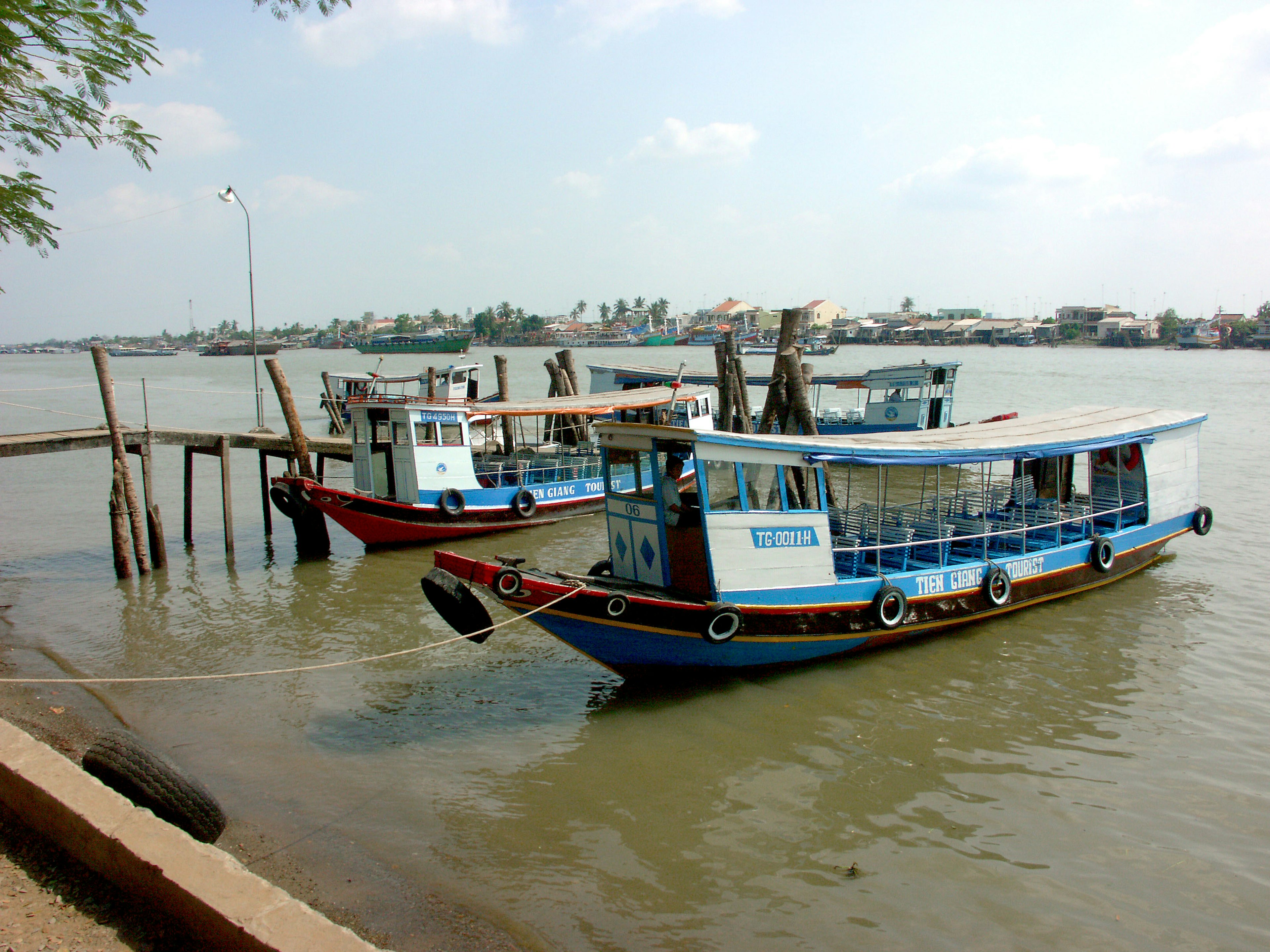 ทิวทัศน์ของเรือสีน้ำเงินและสีแดงจอดอยู่ที่แม่น้ำ