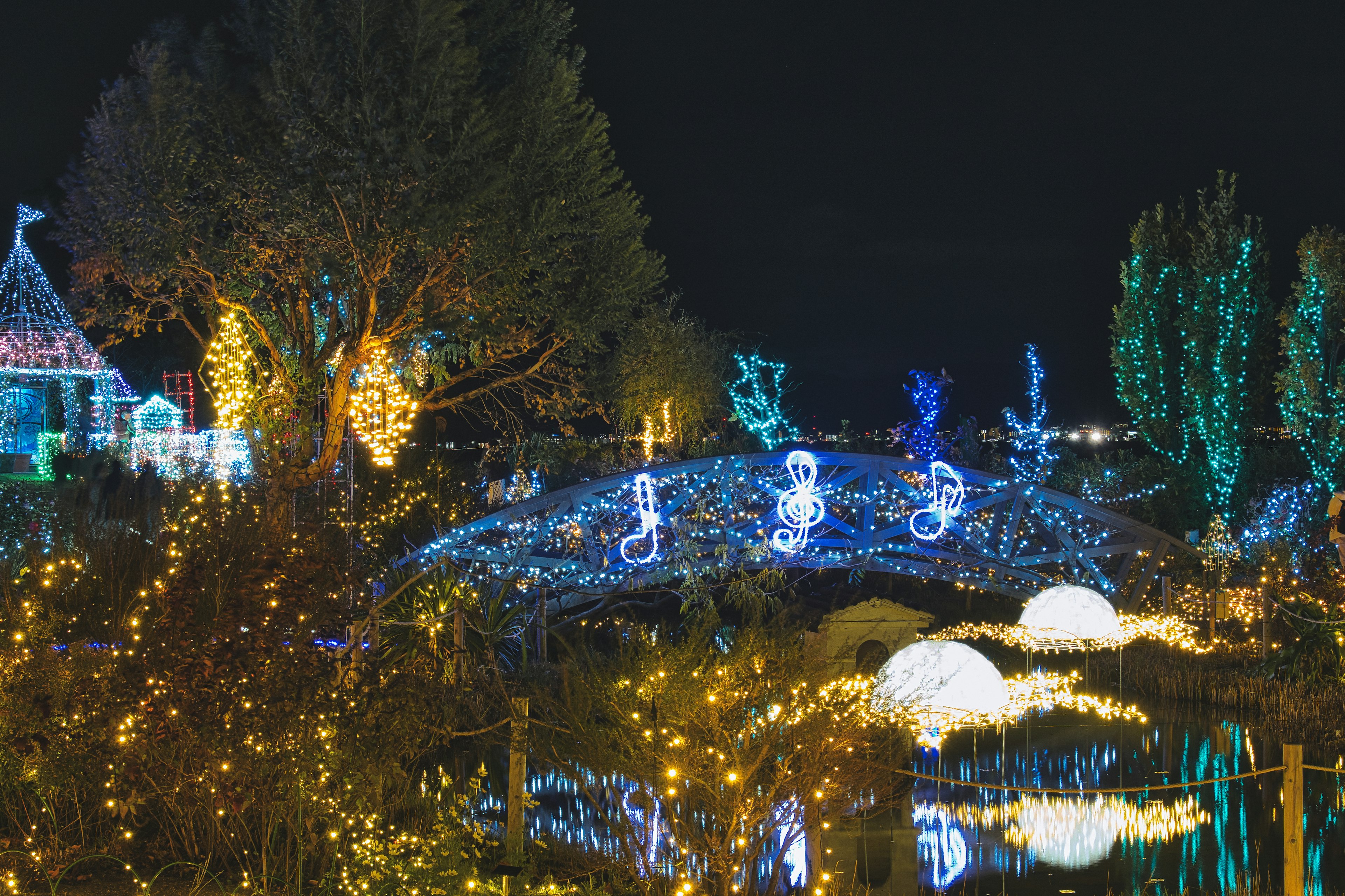 Escena nocturna con un puente decorado con luces en forma de notas musicales y decoraciones vibrantes