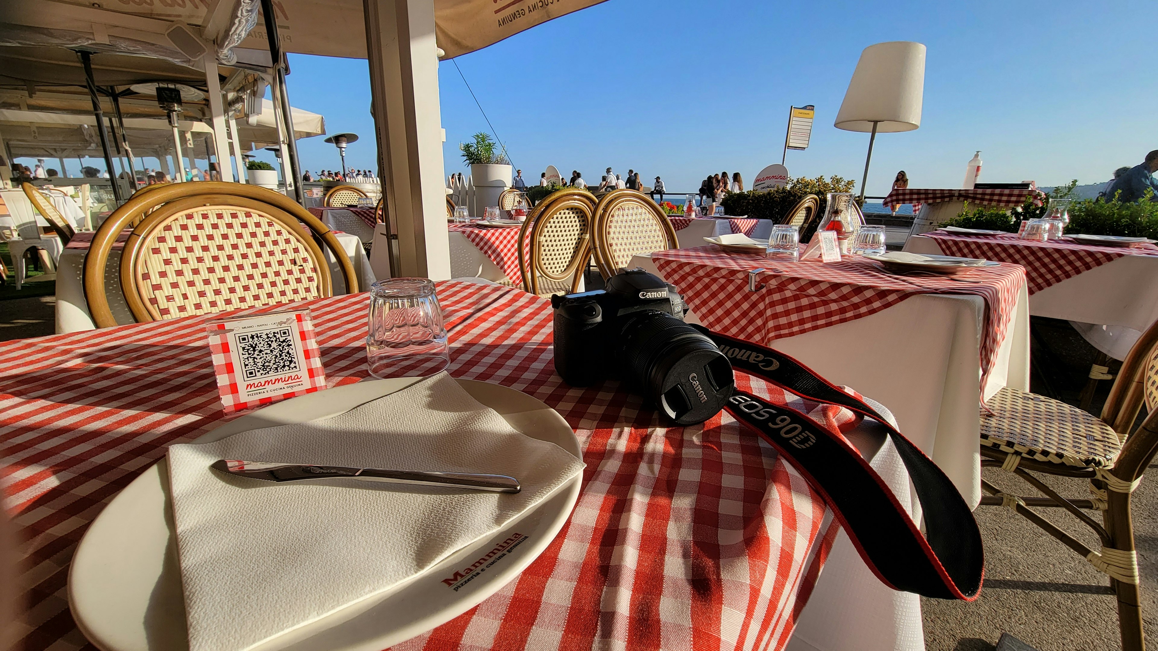 Kamera und Teller auf einem Tisch mit rot-weiß karierter Tischdecke in einem Restaurant im Freien