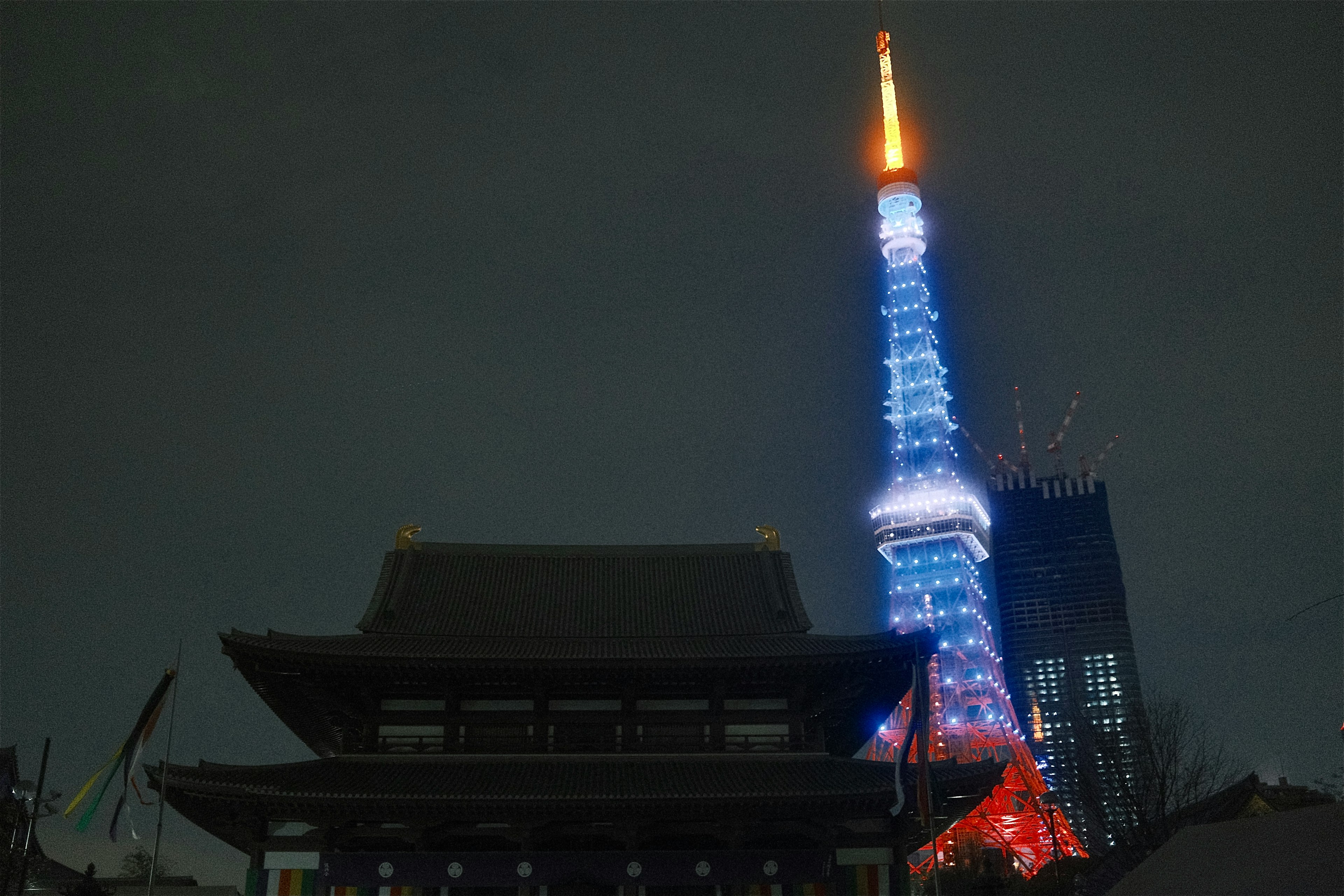 Vue nocturne de la tour de Tokyo illuminée avec un bâtiment traditionnel au premier plan