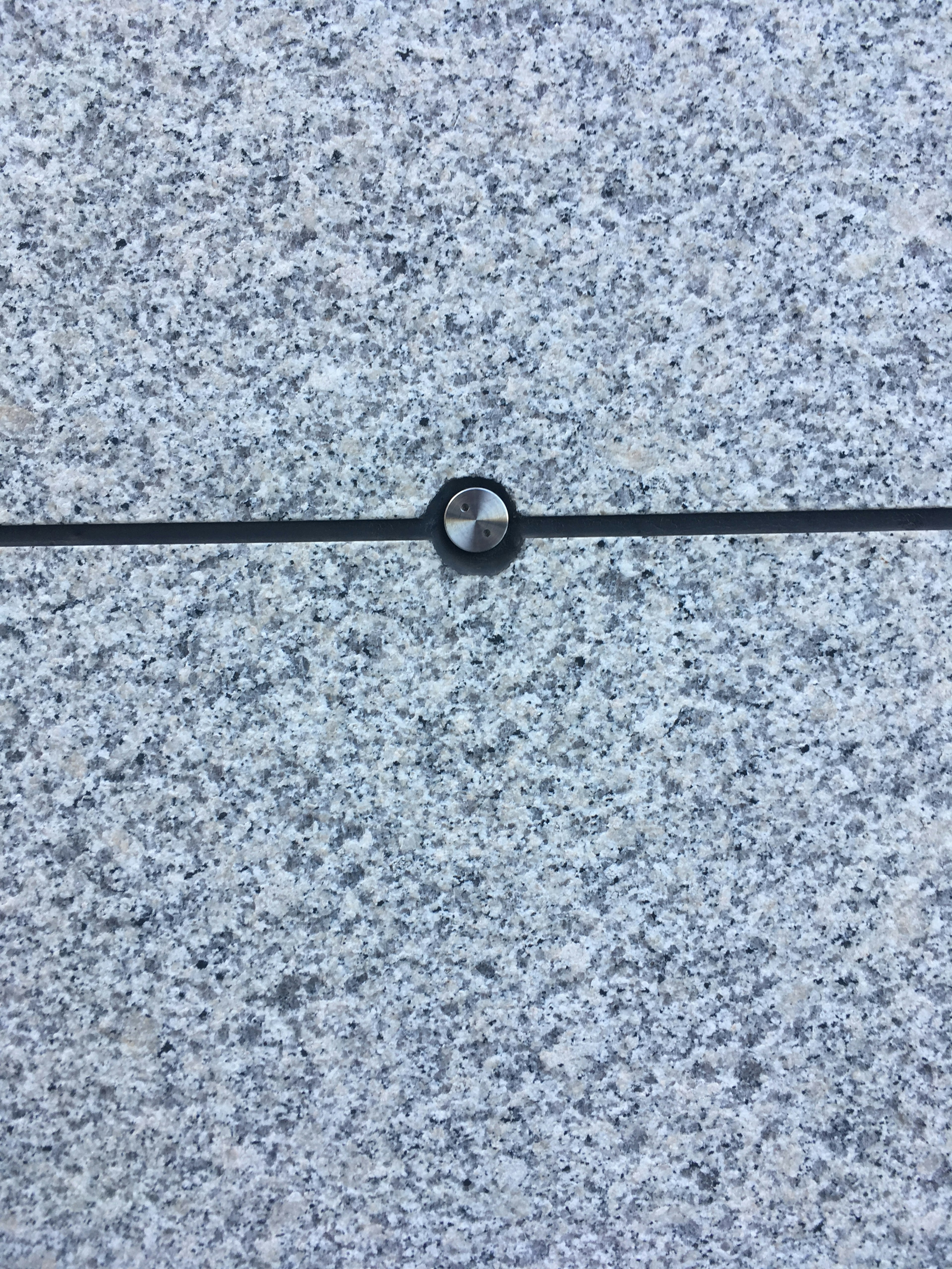 Gray stone surface with a black line and a circular hole