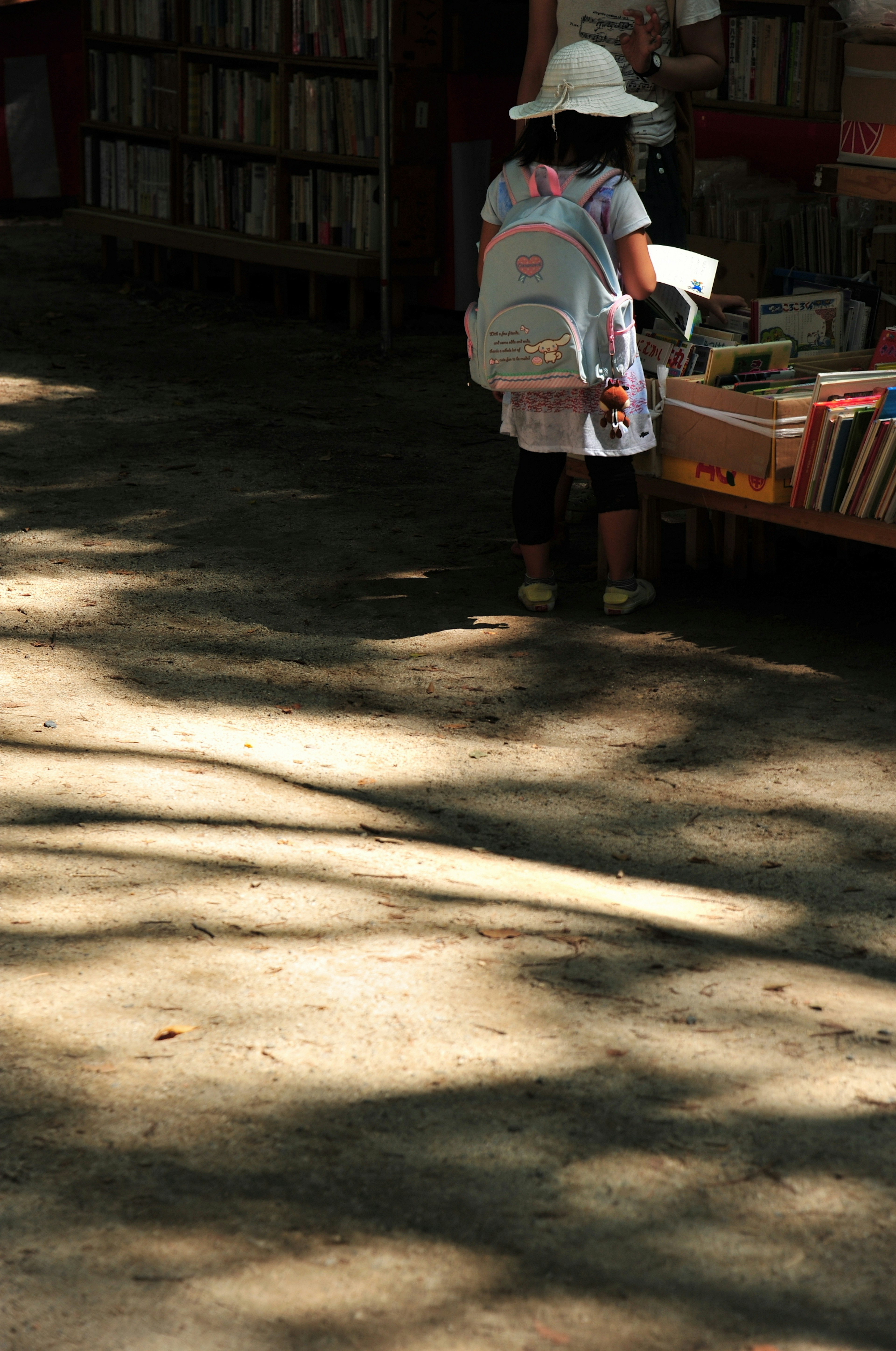 Anak yang memegang buku berdiri di depan toko buku