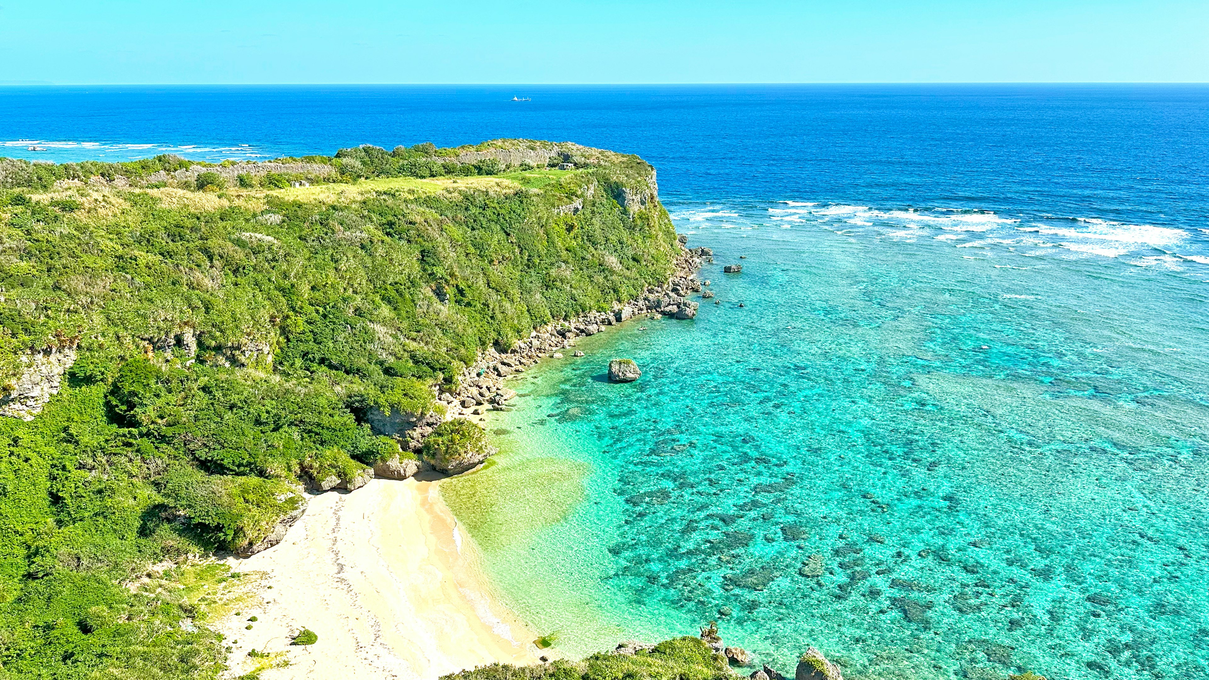 Vista panoramica di un oceano turchese e scogliere verdi con una spiaggia sabbiosa