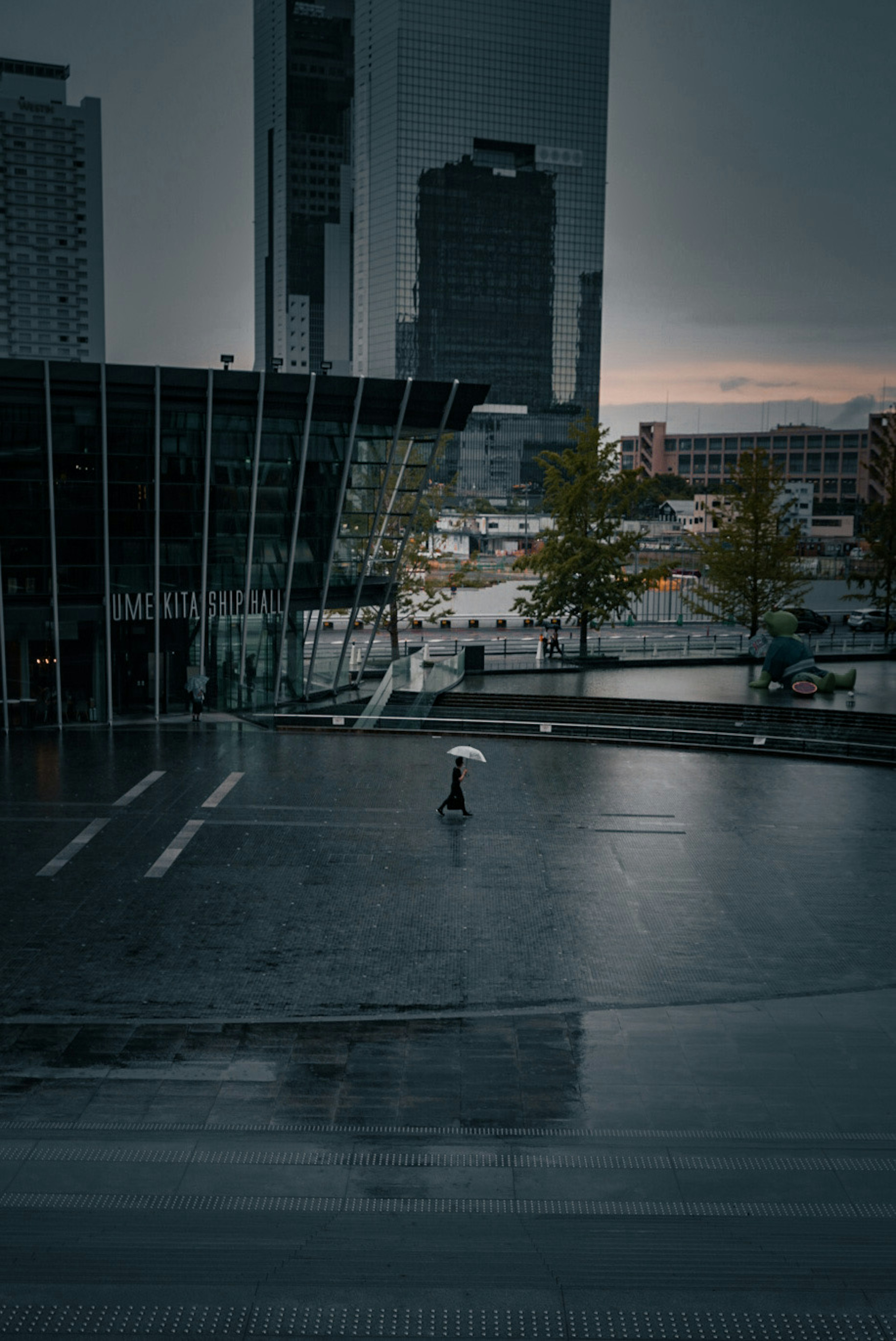 Eine einsame Figur steht in einer dunklen urbanen Landschaft mit Gebäude-Reflexionen