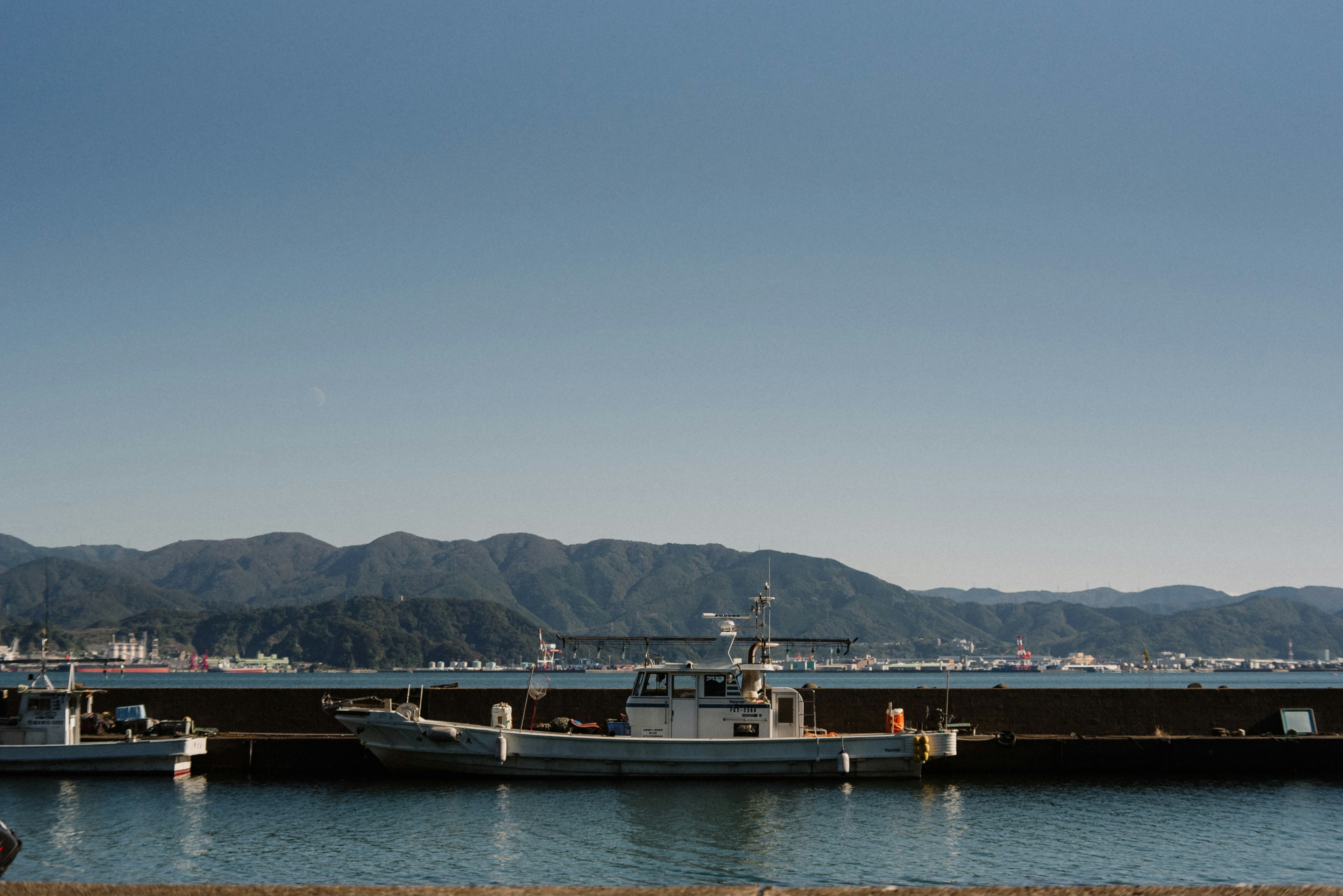 Vista de barcos atracados en un puerto con montañas al fondo