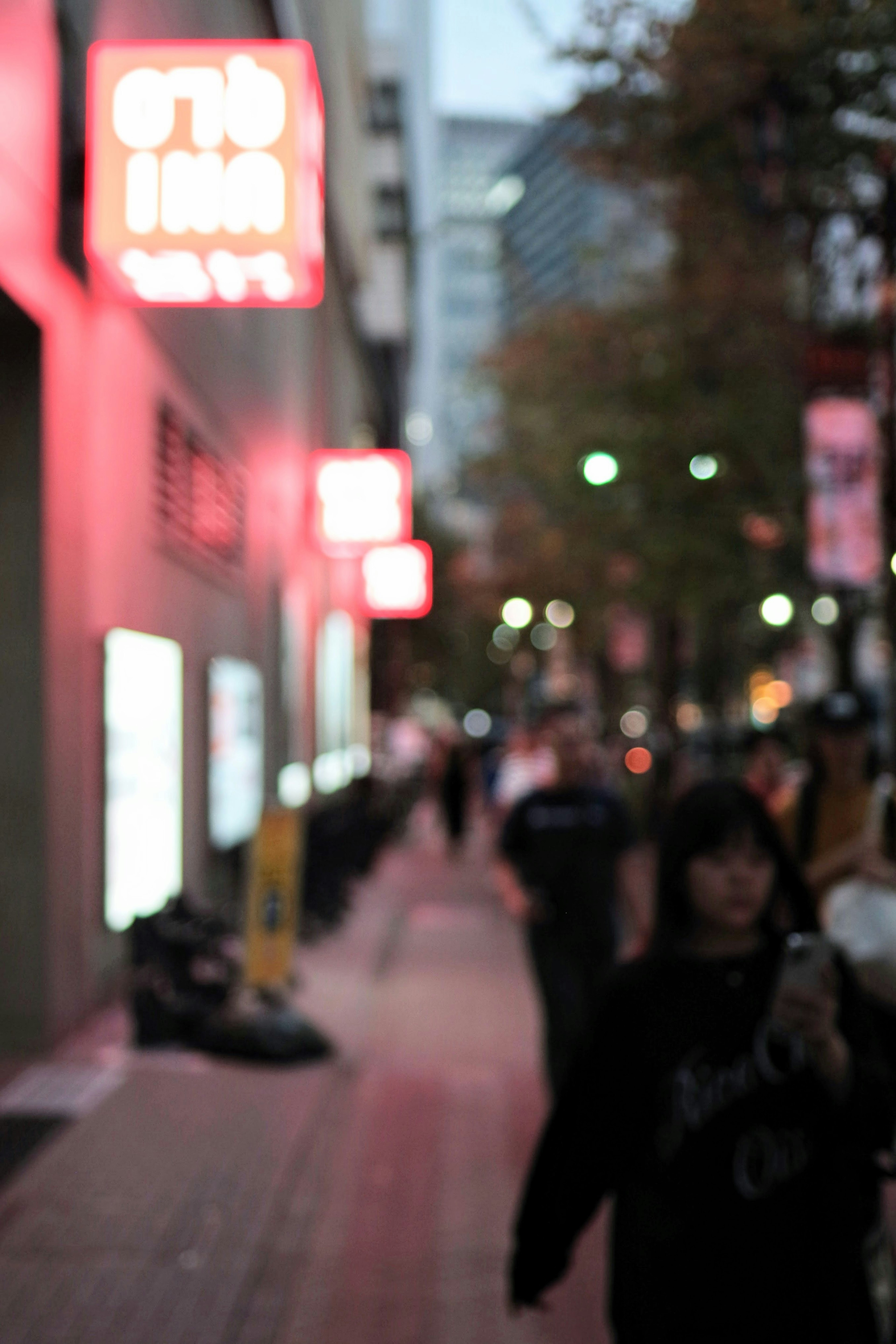 Blurred street scene in a city illuminated by streetlights and red signs at night