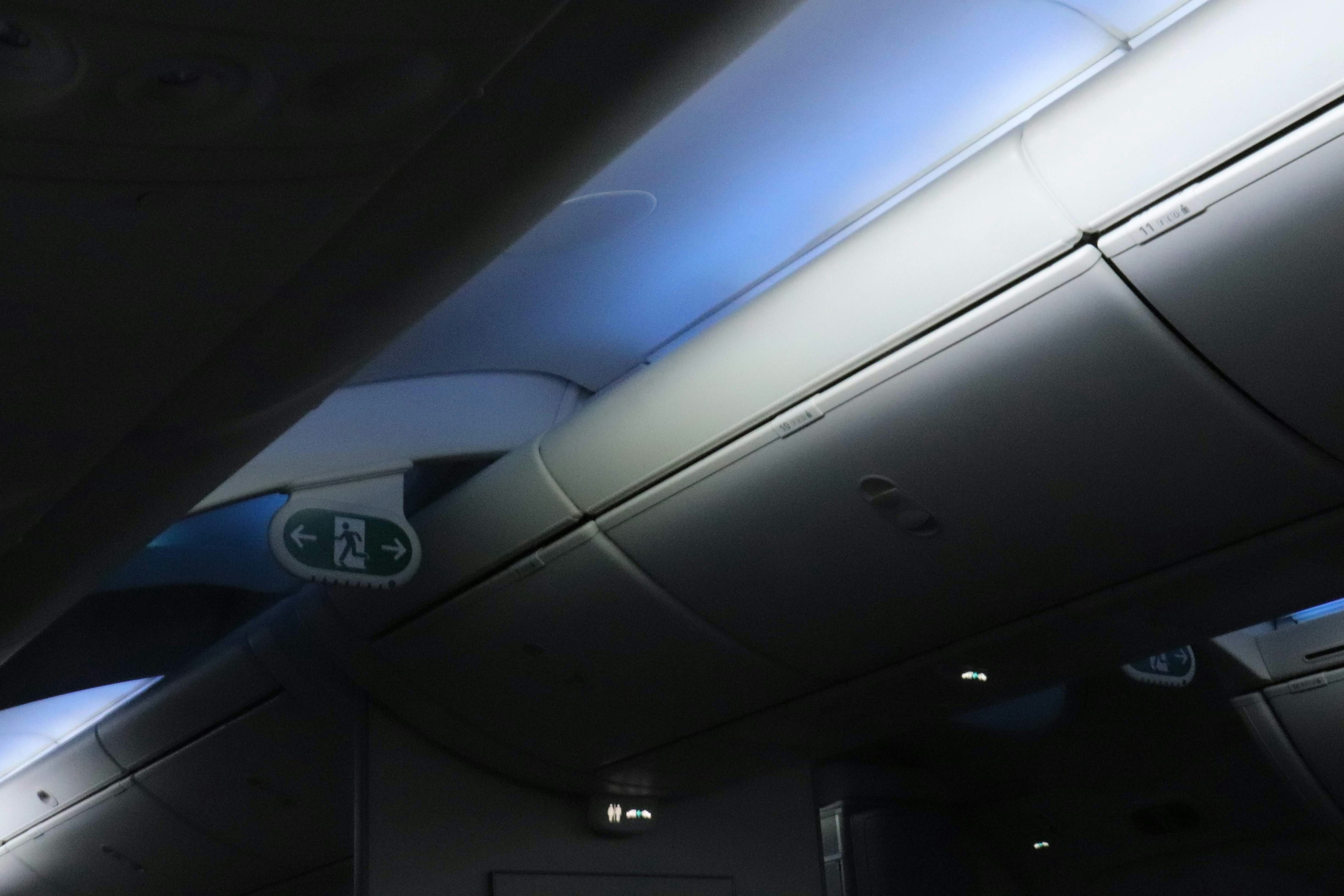 Close-up of airplane interior ceiling featuring blue lighting and smooth surfaces