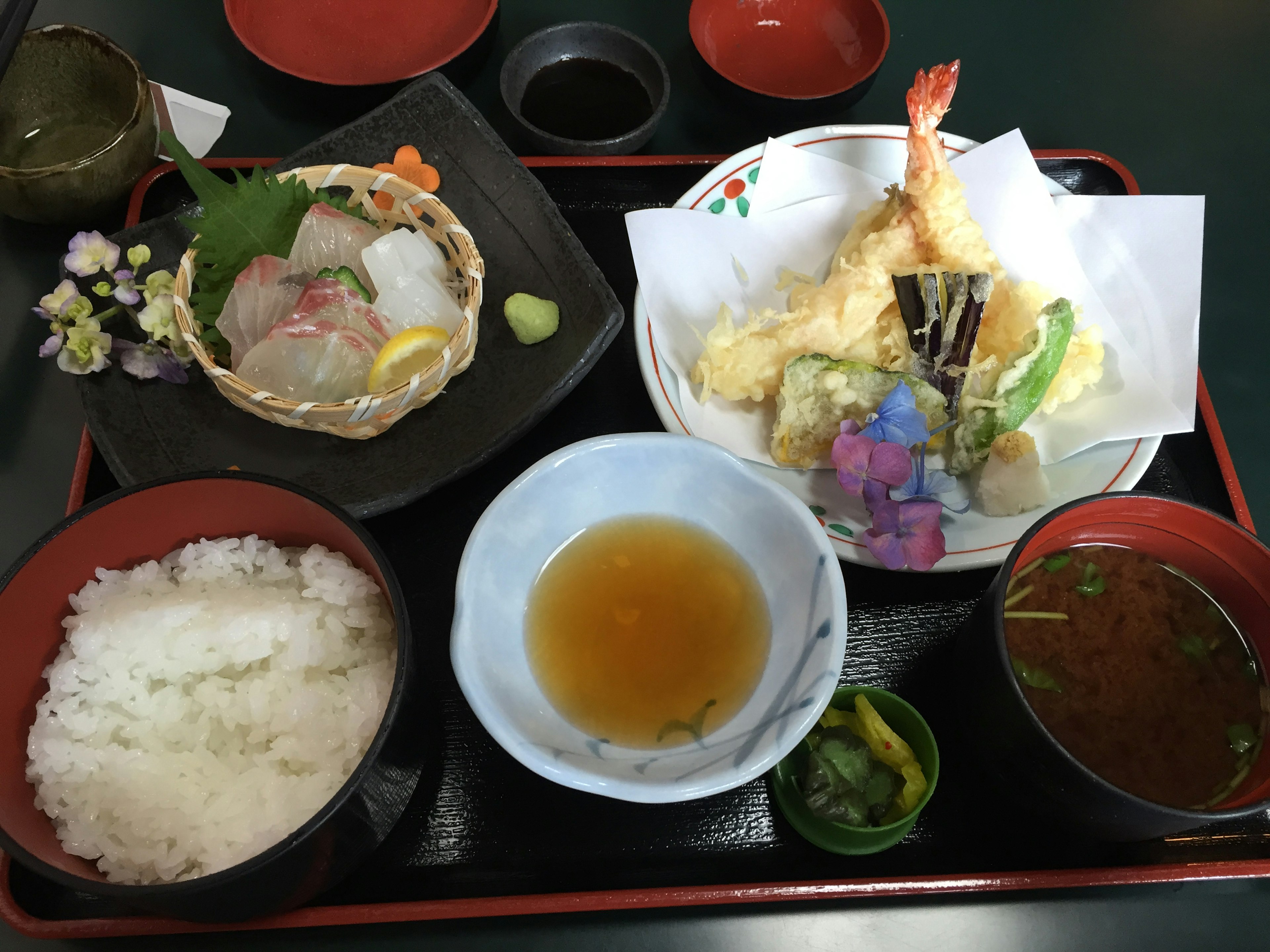 Una comida japonesa tradicional que incluye tempura sashimi y arroz blanco