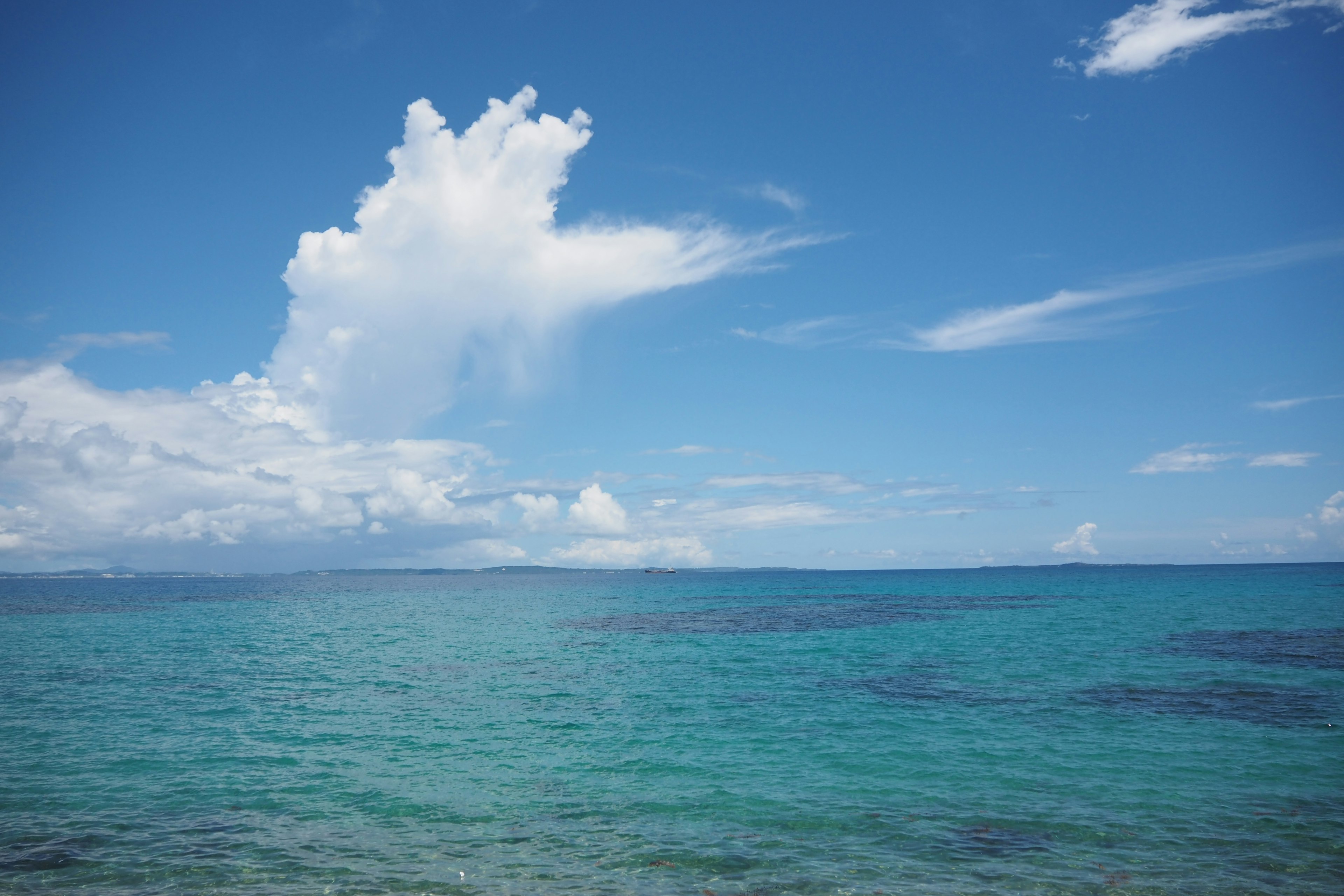 Laut biru dengan awan putih mengapung di langit cerah