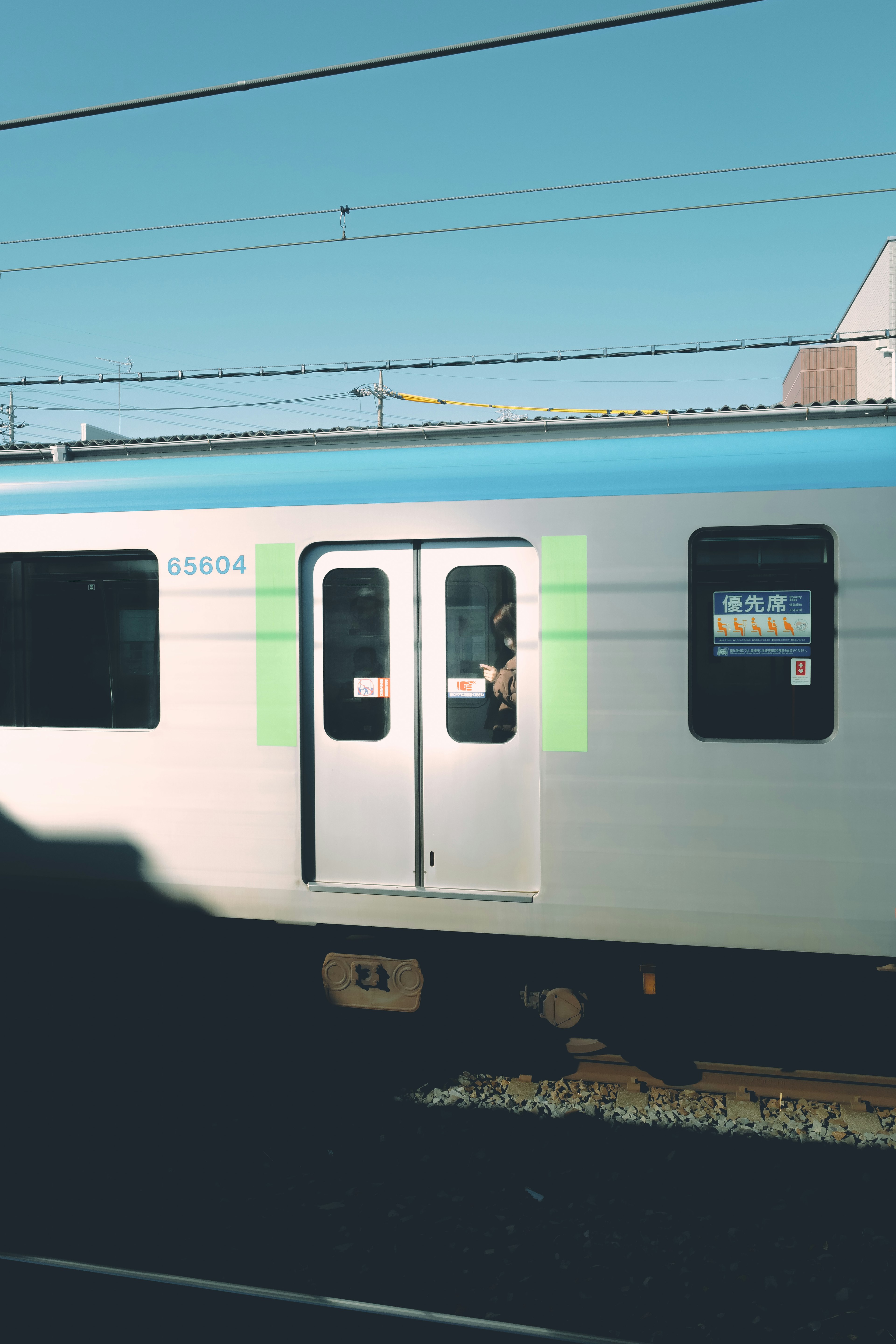 青空の下にある電車の側面　ドアが白と緑のデザイン