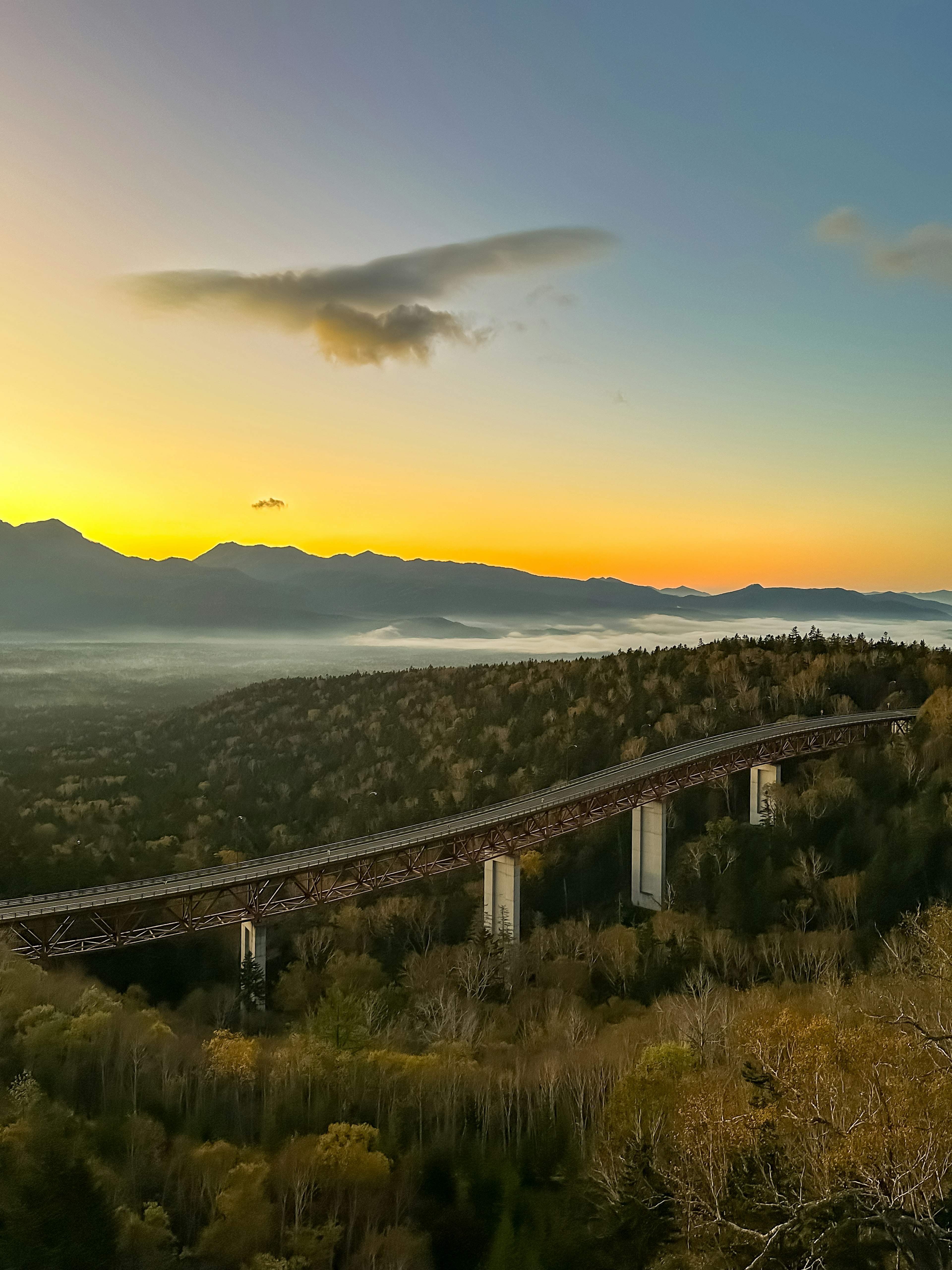 Vue panoramique d'un pont au coucher du soleil avec des montagnes et des vallées en arrière-plan