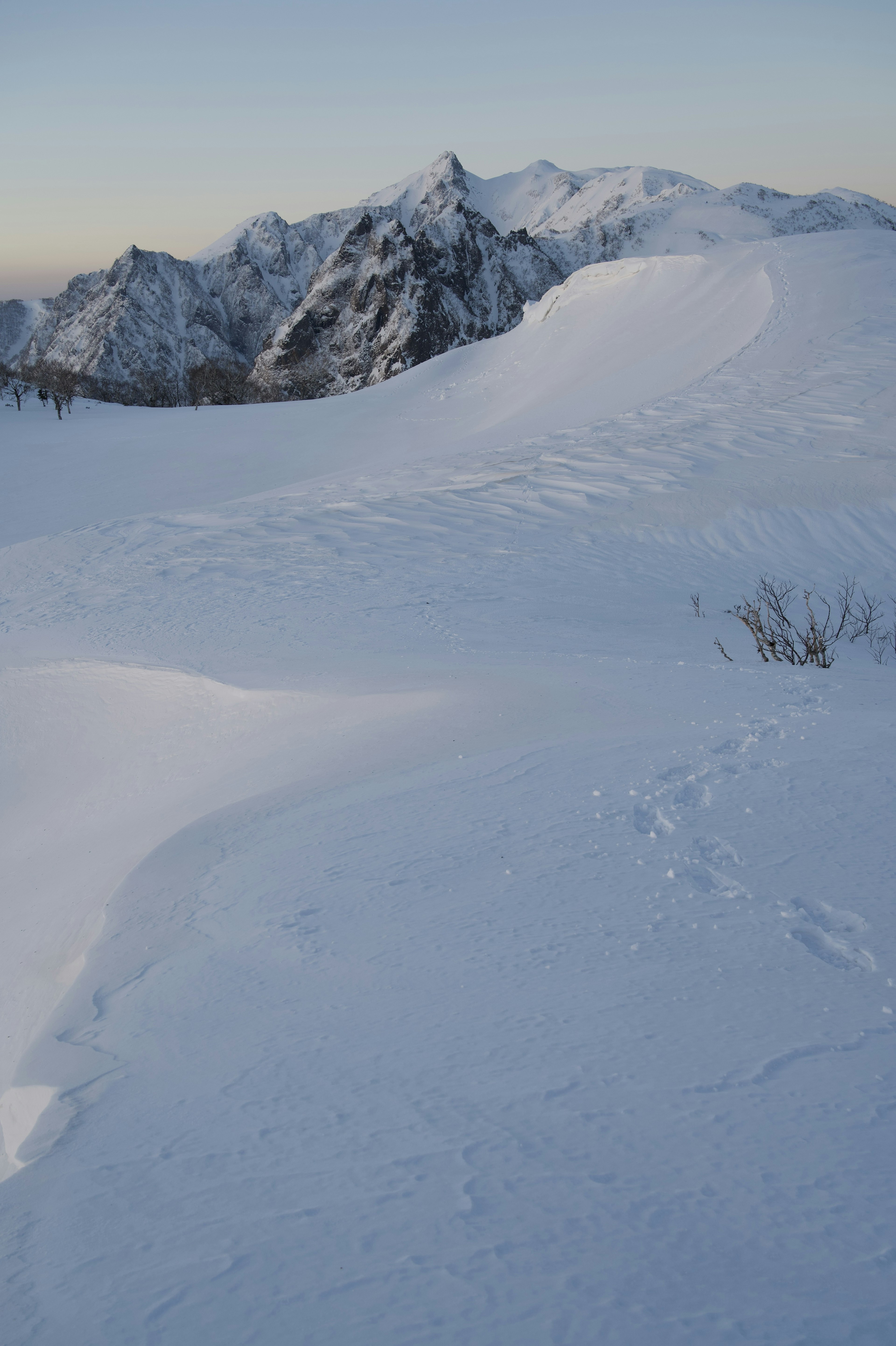 Paisaje montañoso cubierto de nieve con picos a lo lejos