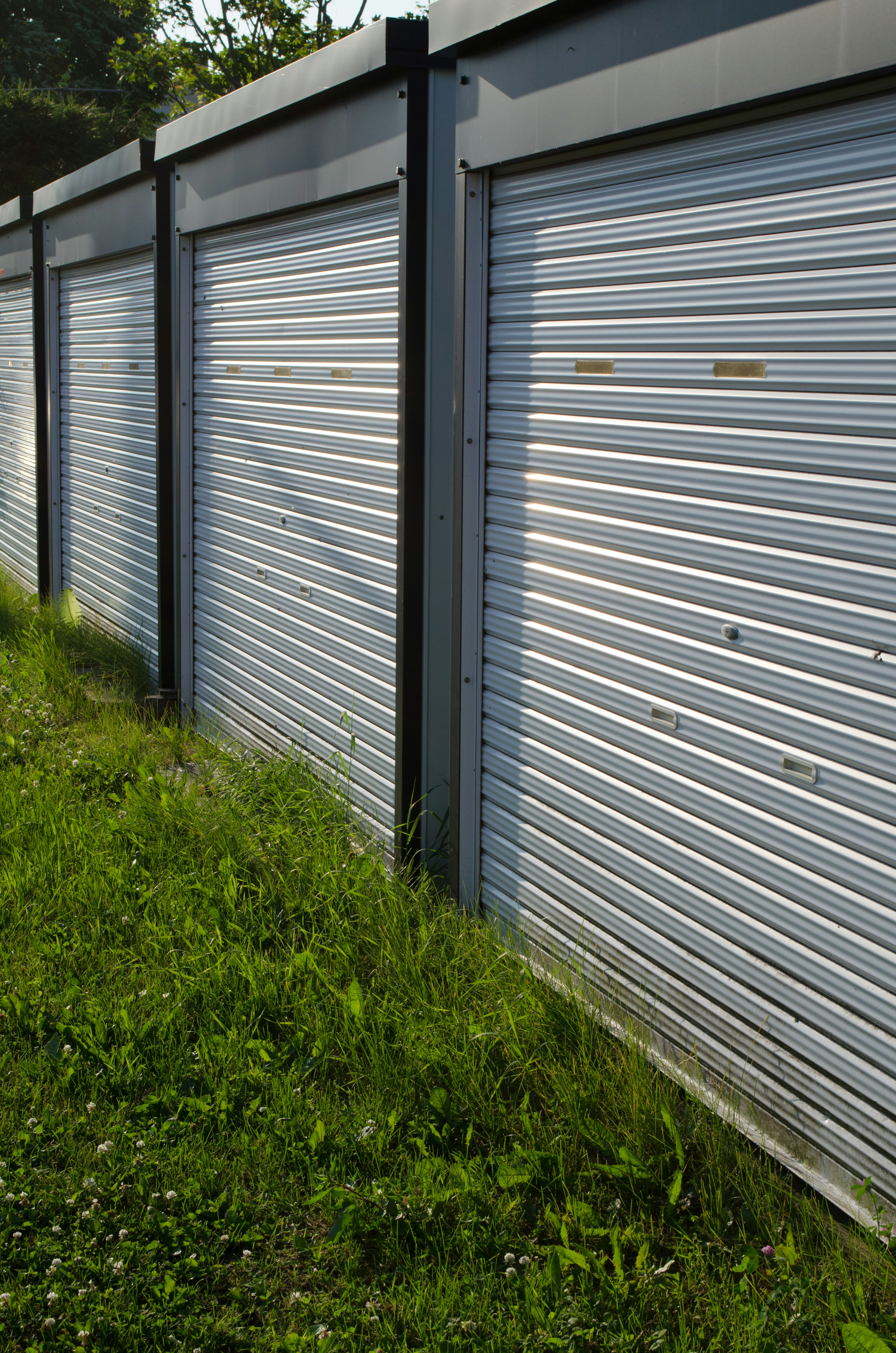 Metal shutters lined up on a warehouse wall with green grass in front