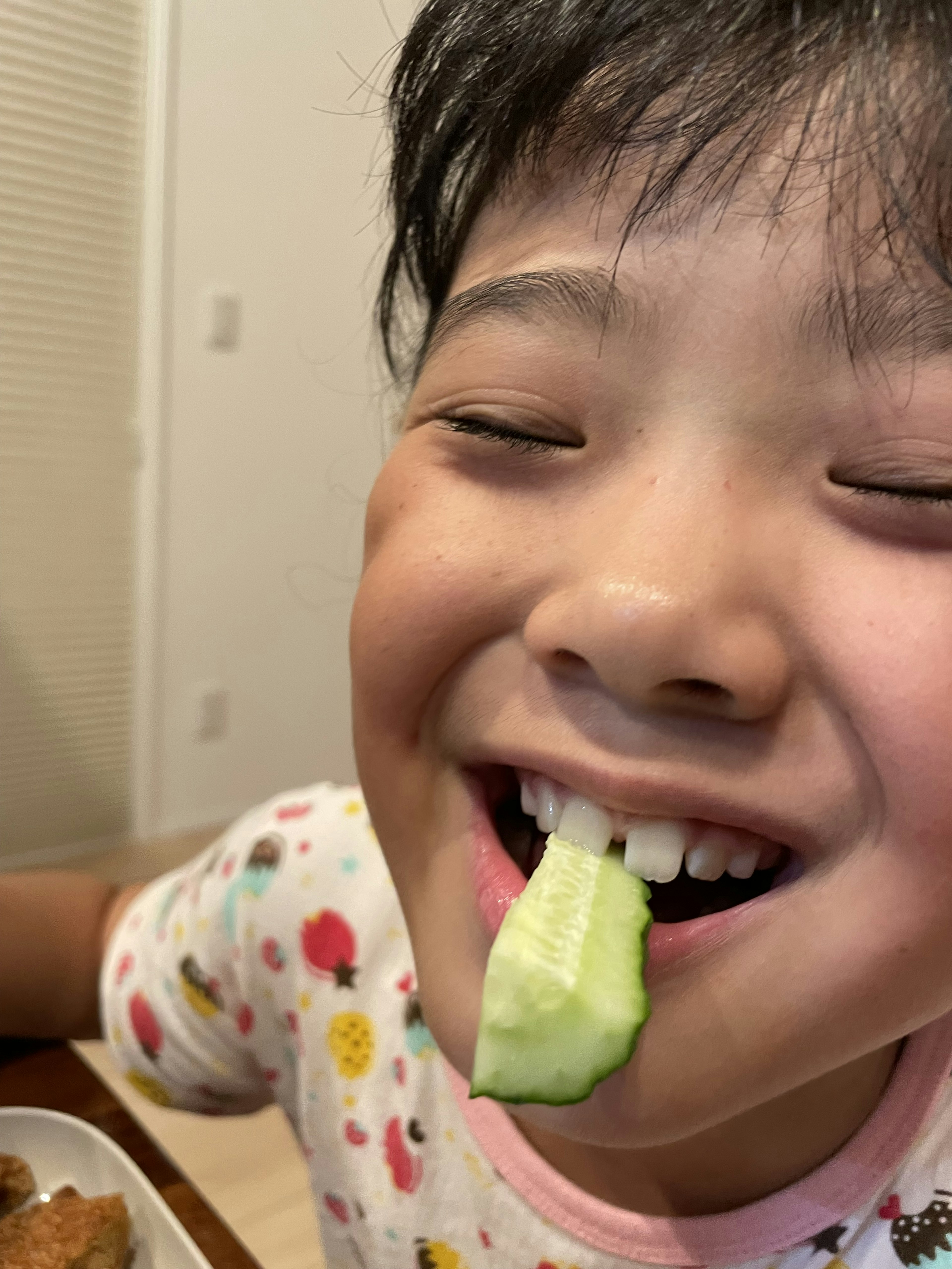 Enfant souriant avec un concombre dans la bouche