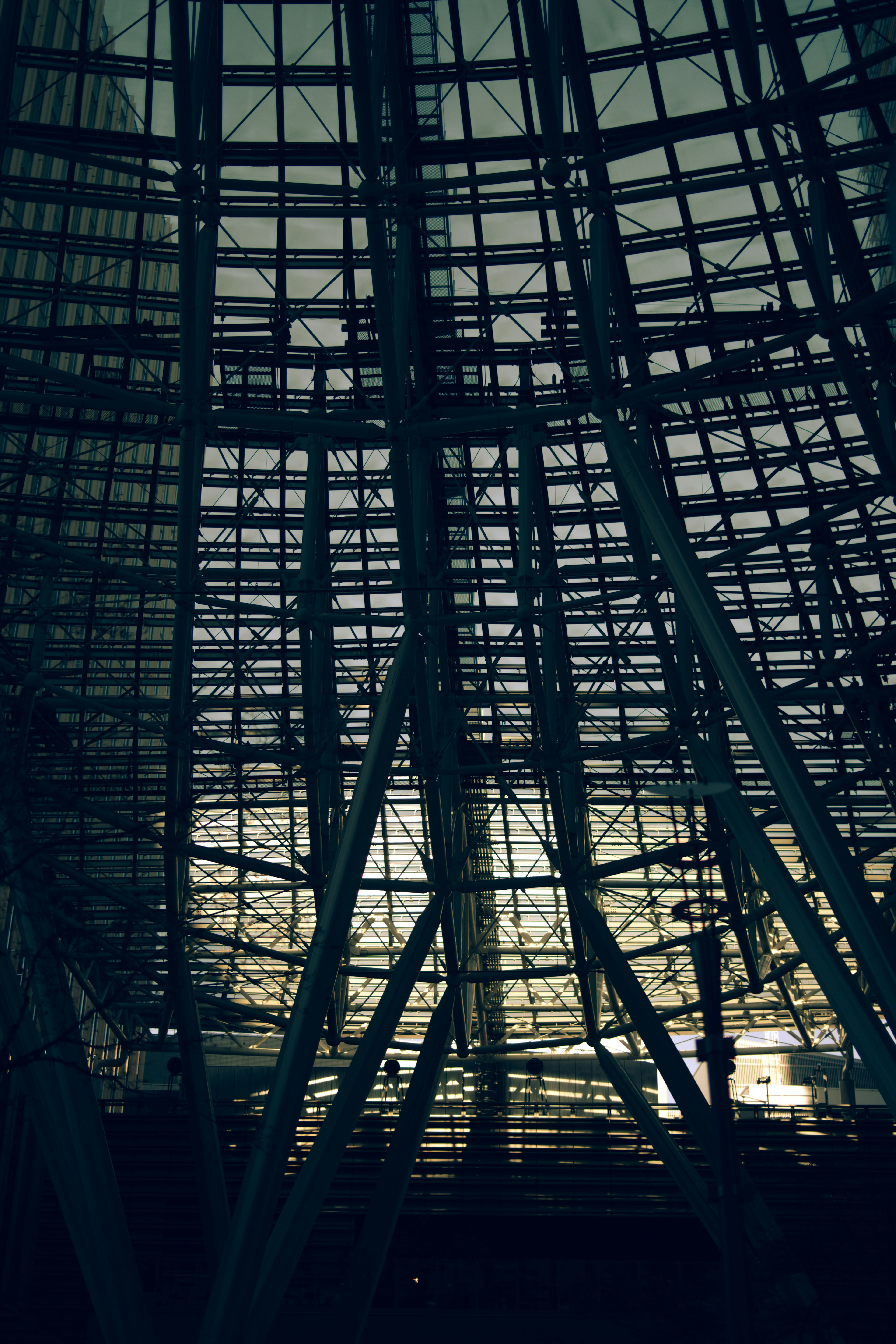 Vista interior de una estructura de vidrio y metal con reflejos y sombras impactantes