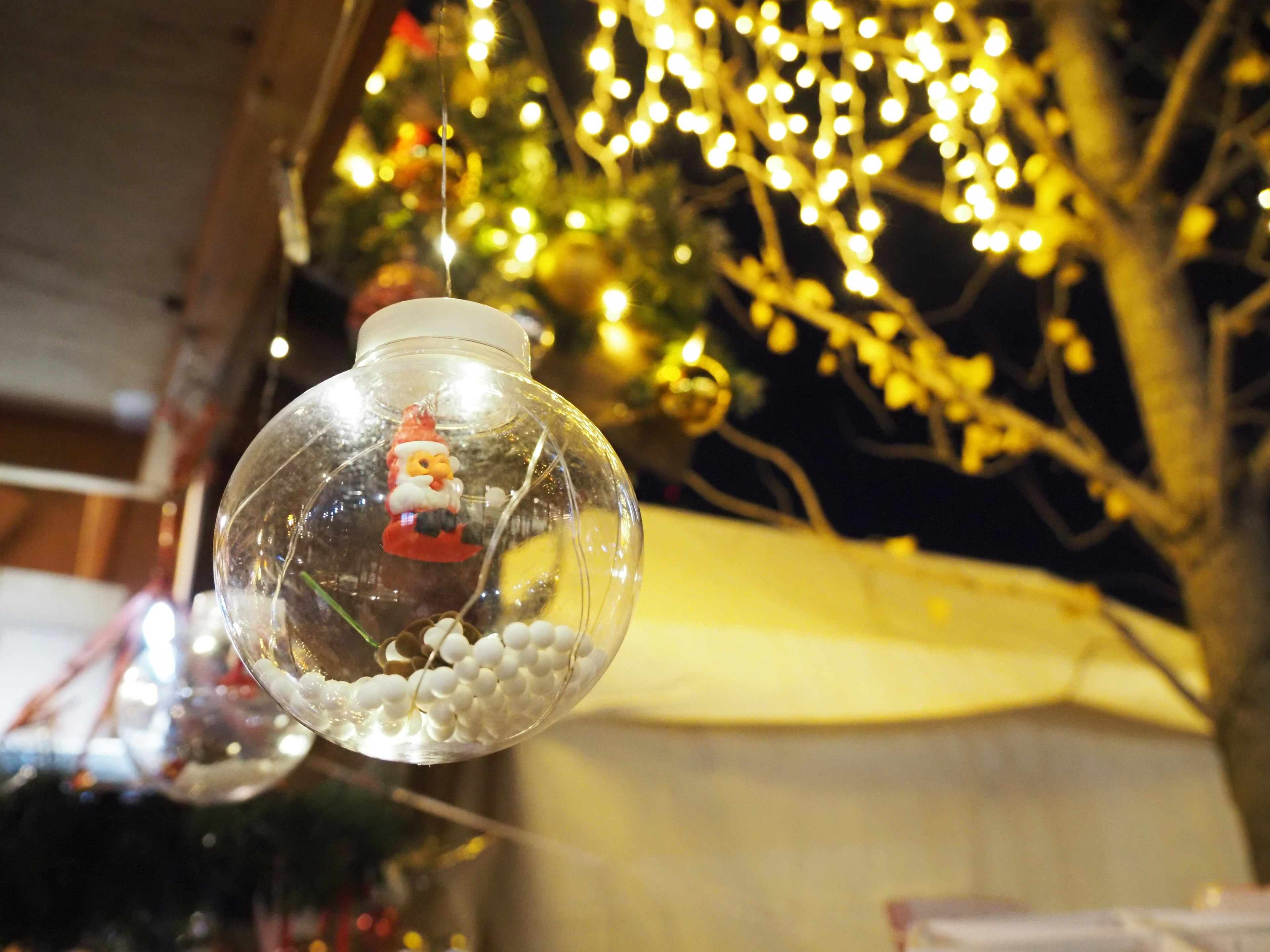 Glass ornament with Santa inside and bright holiday lights in the background