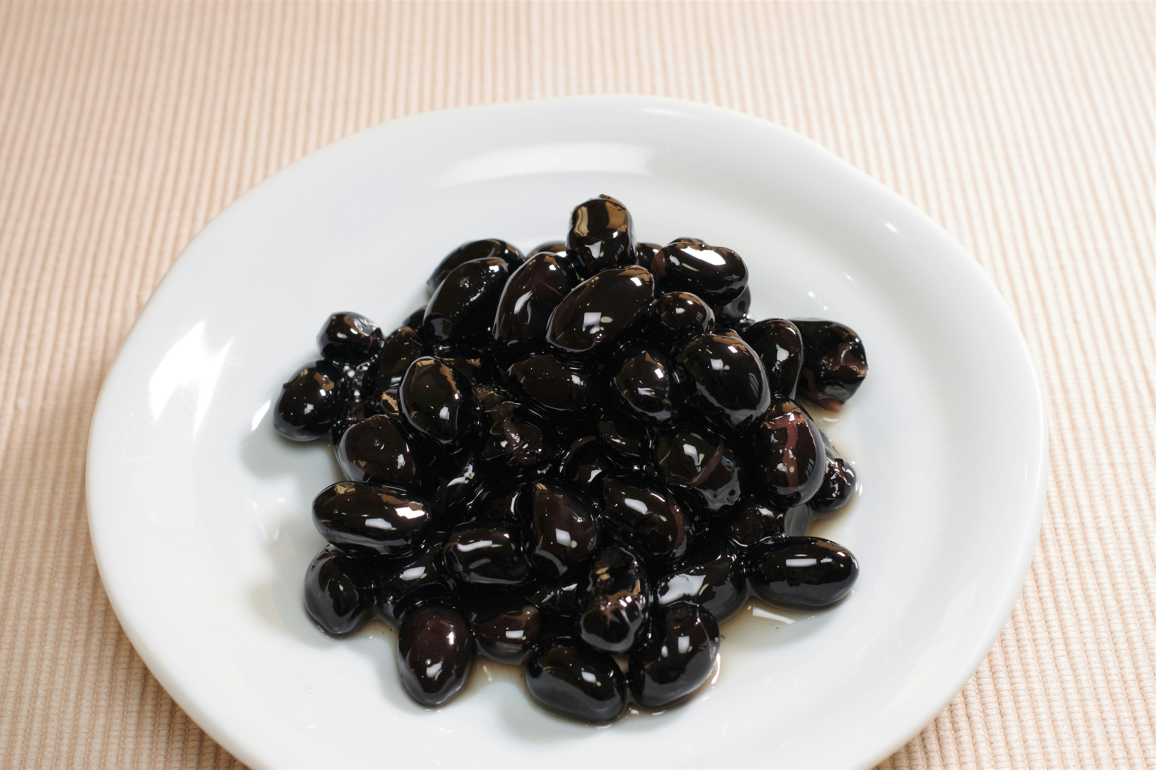 A white plate filled with shiny black beans