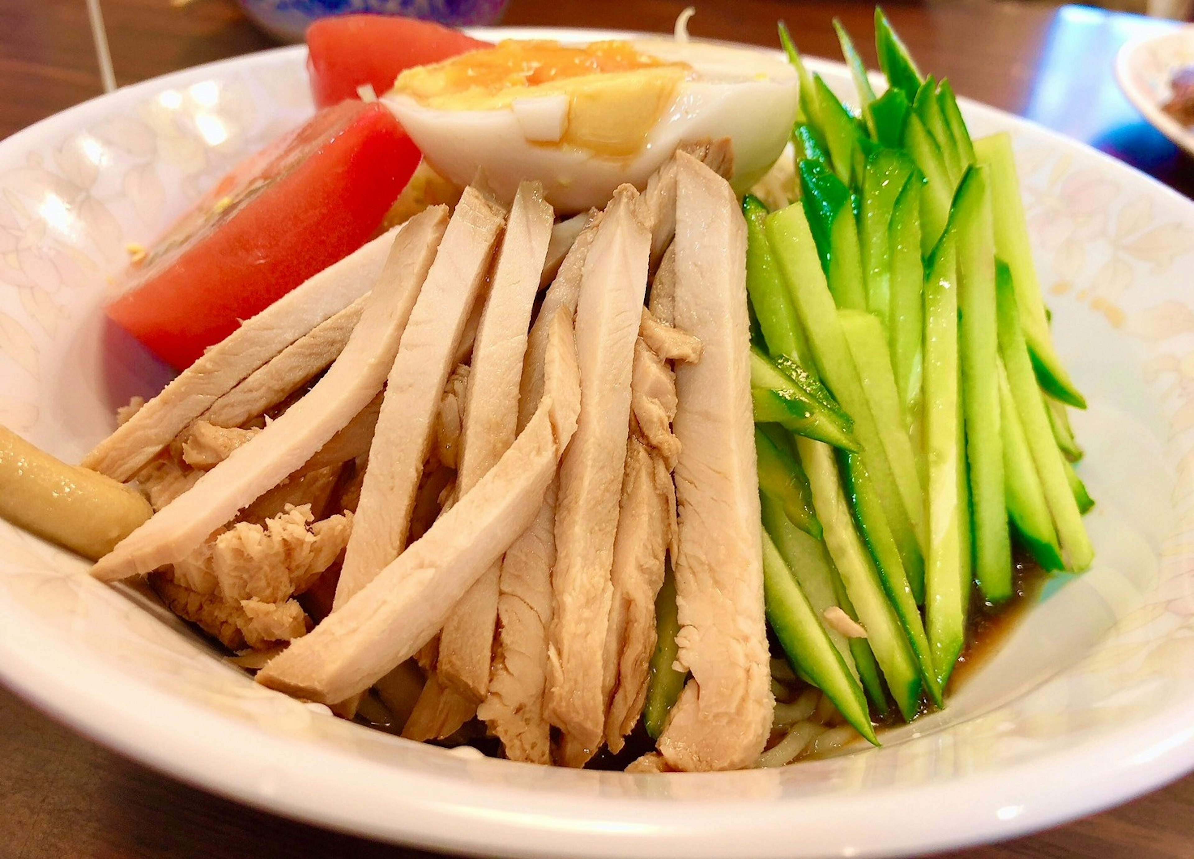 Plate of sliced chicken with cucumber, tomato, and boiled egg