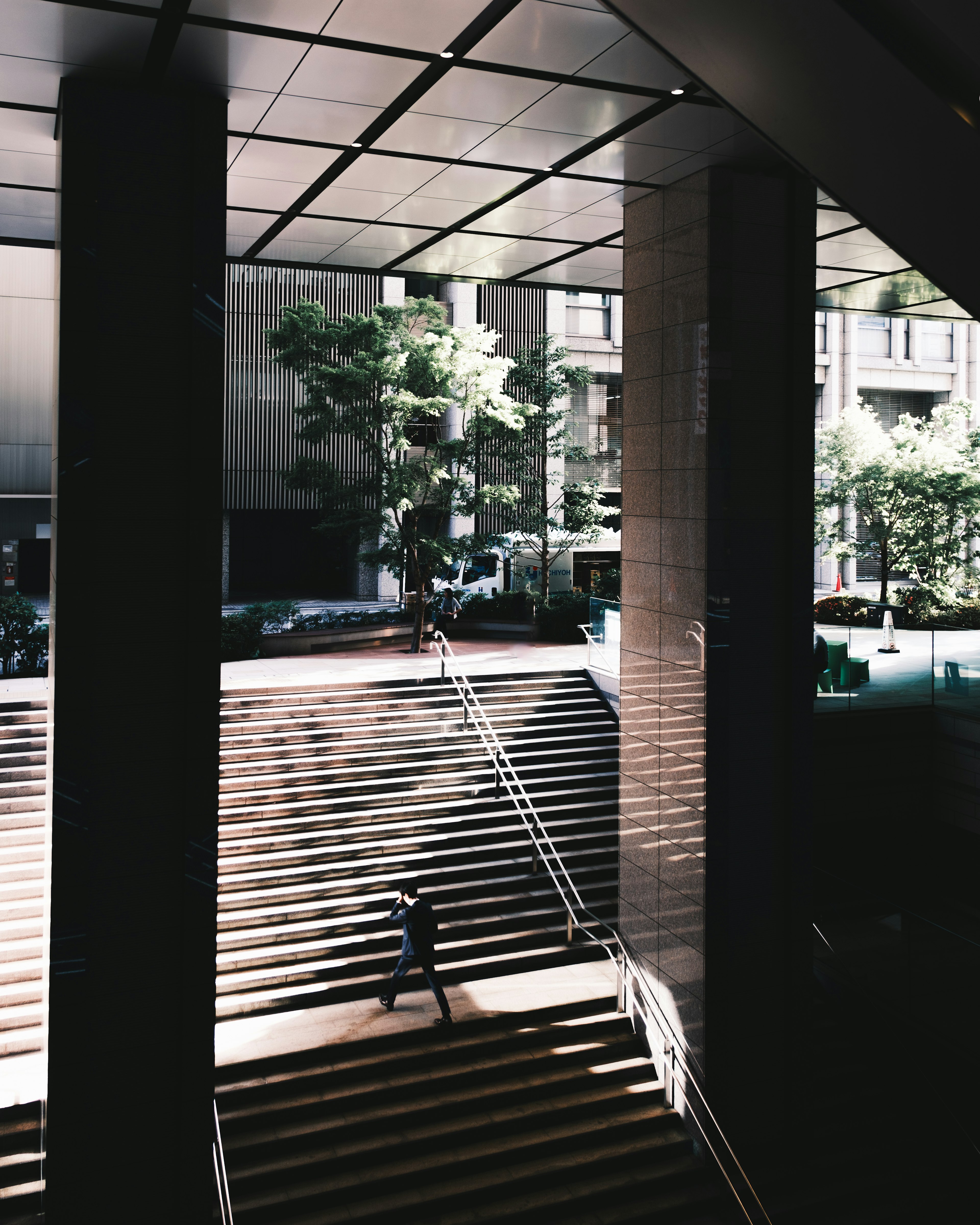 Escena urbana con una persona bajando escaleras y sombras de edificios circundantes