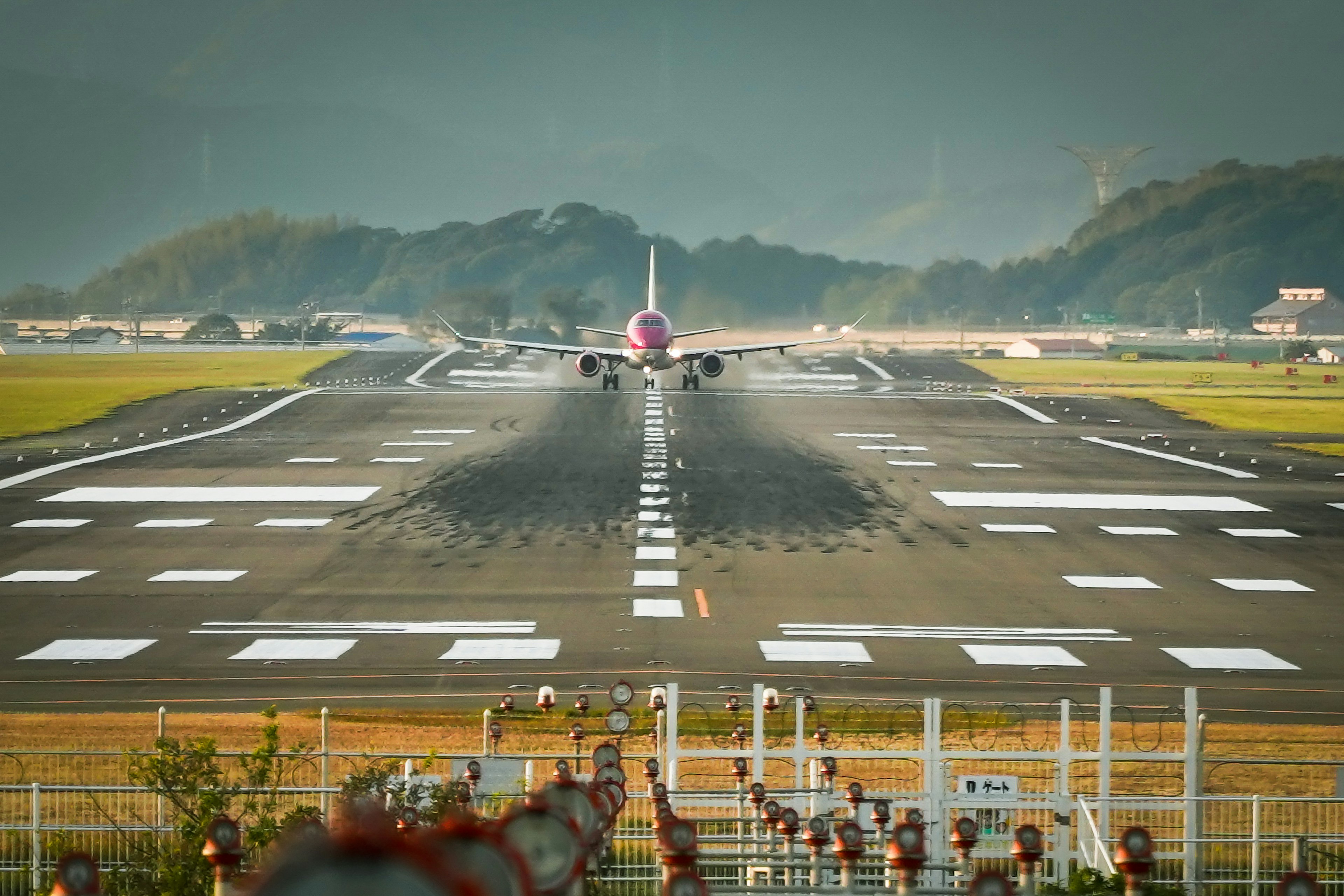 滑走路に向かう飛行機の後方の風景で、背景には山々が見える