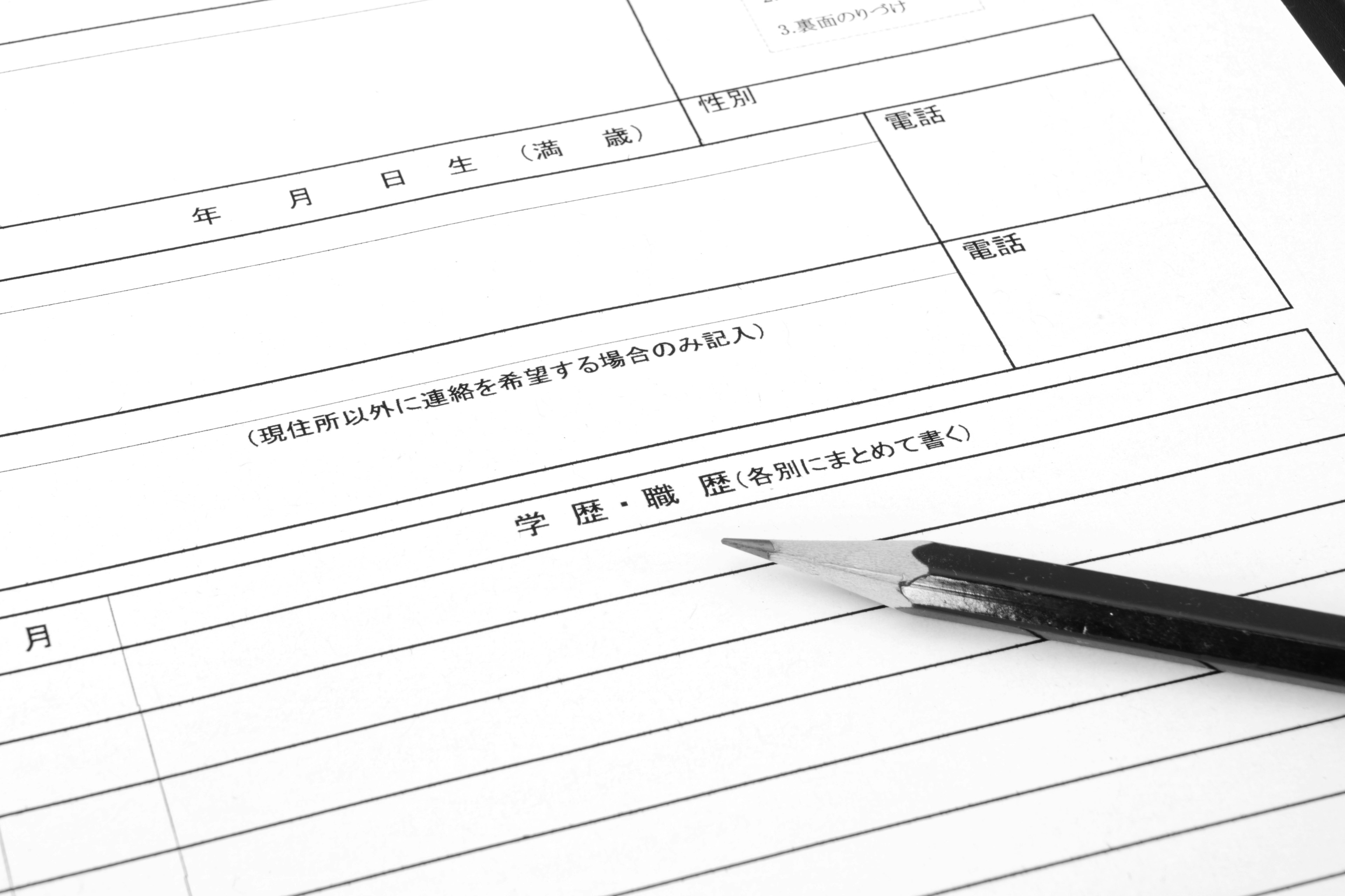 白い用紙に横線が引かれた書類と黒い鉛筆