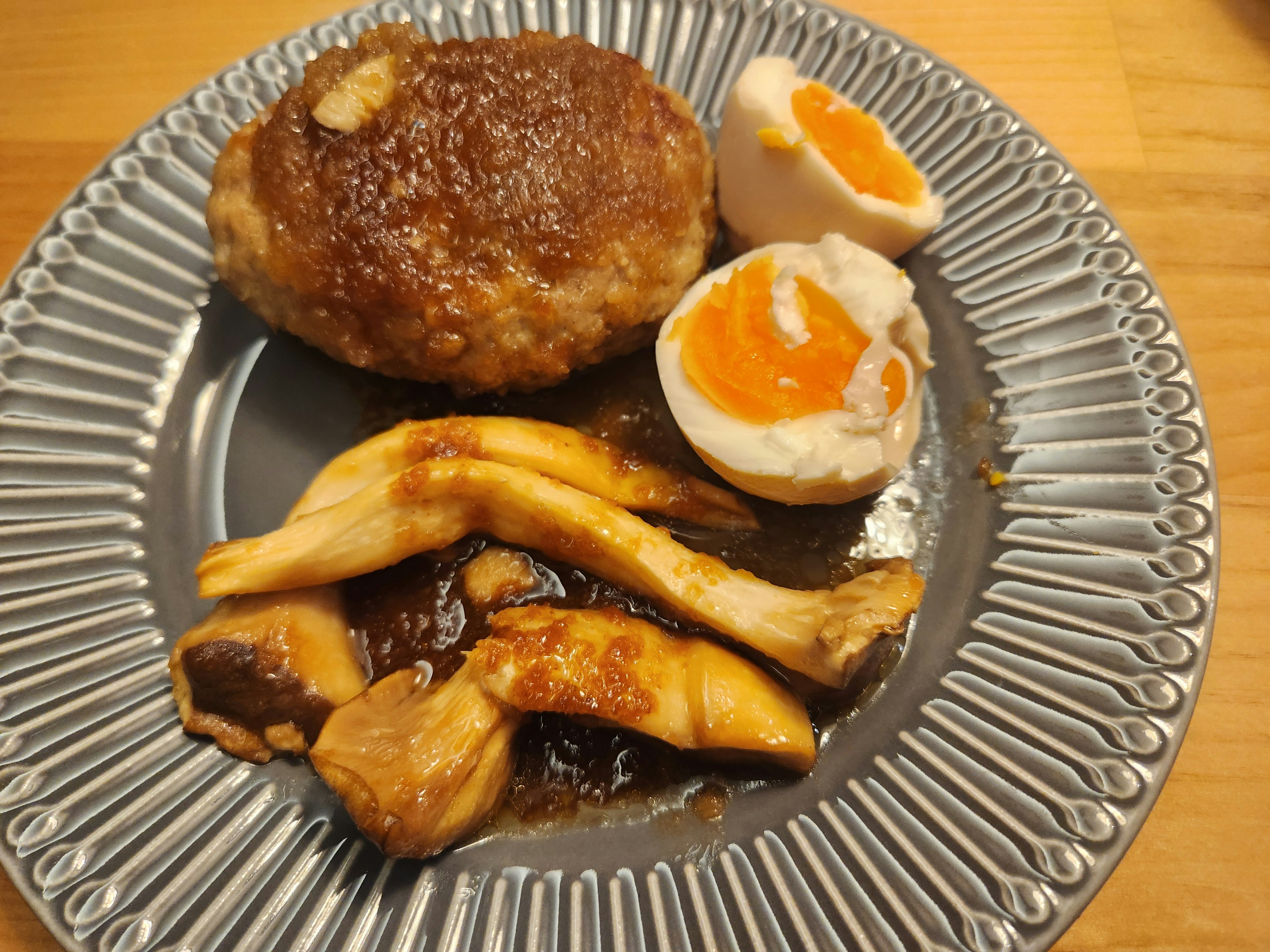 A plate with hamburger steak, soft-boiled eggs, and sautéed mushrooms