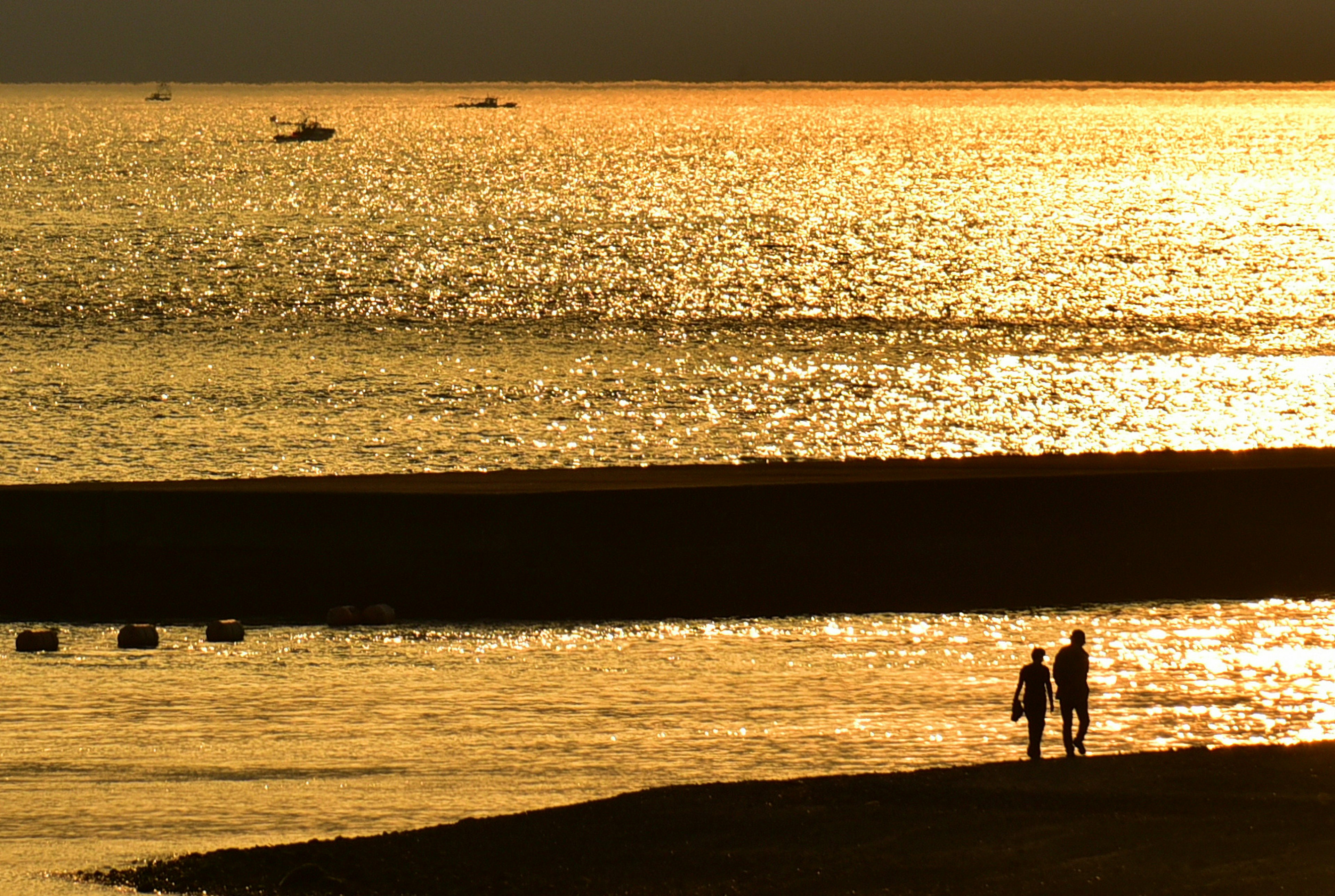 Silhouette di due persone che camminano su una spiaggia al tramonto