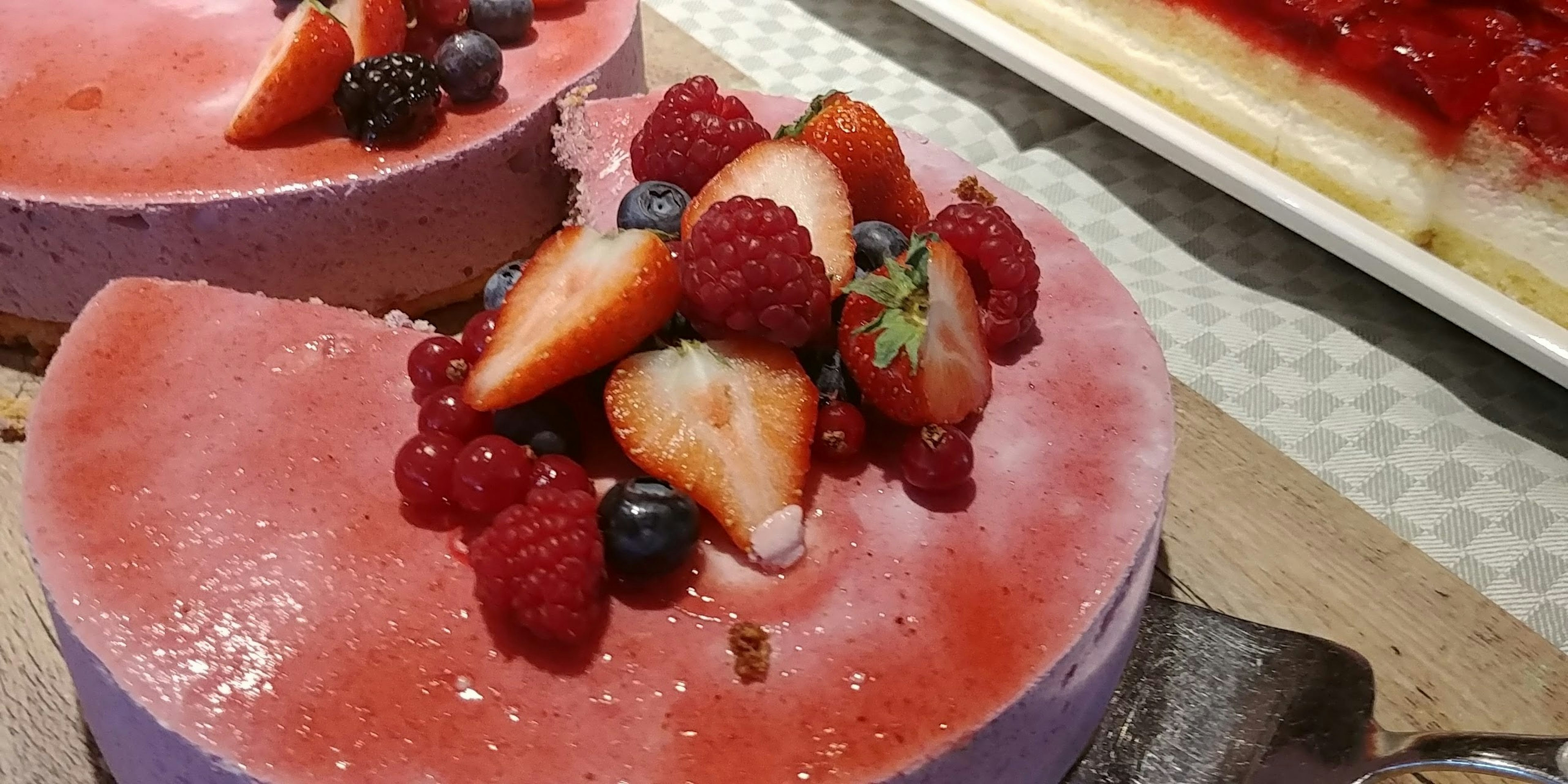 Pastel morado decorado con frutas frescas, incluyendo fresas y frambuesas