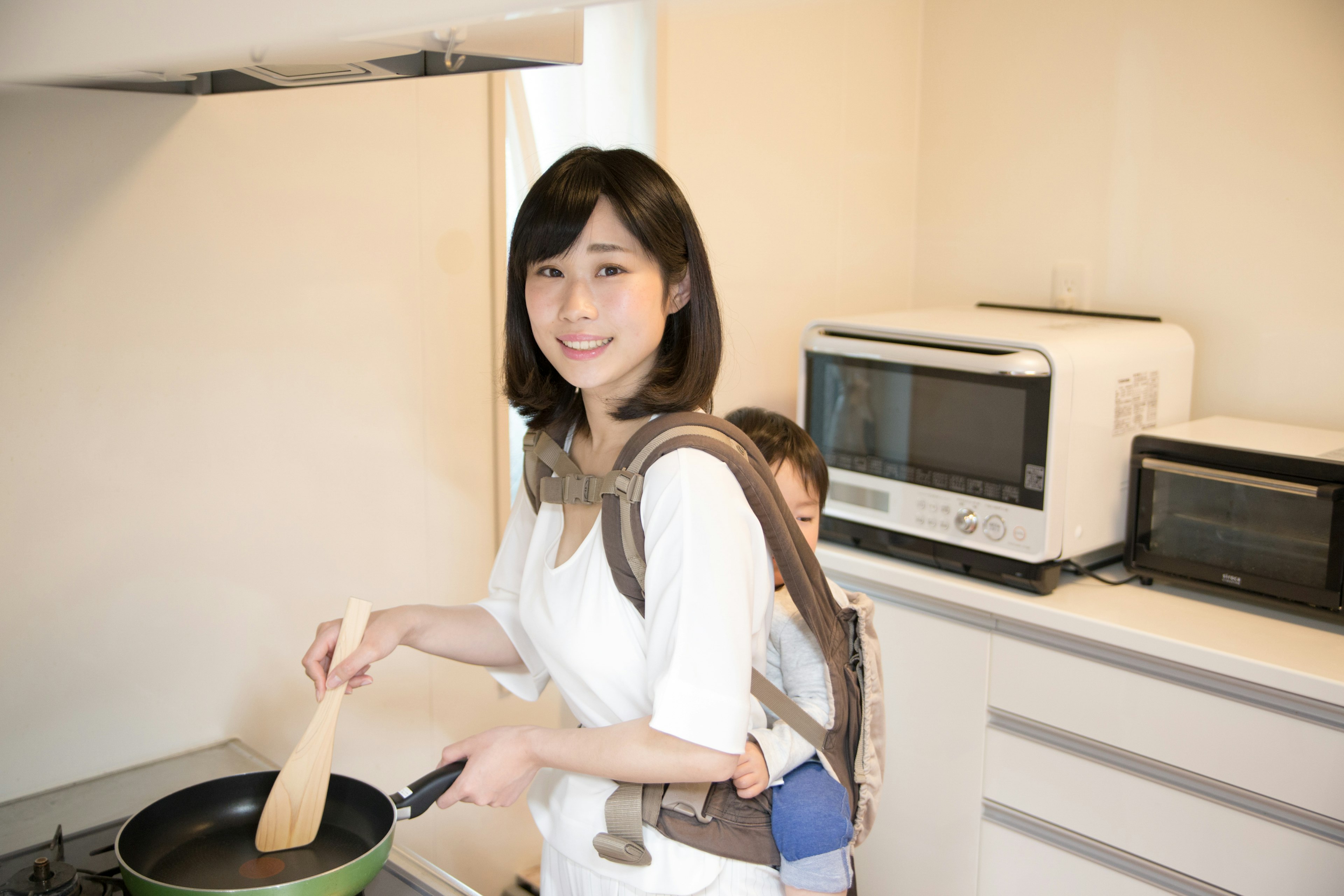 Mère cuisinant dans la cuisine avec un enfant sur le dos